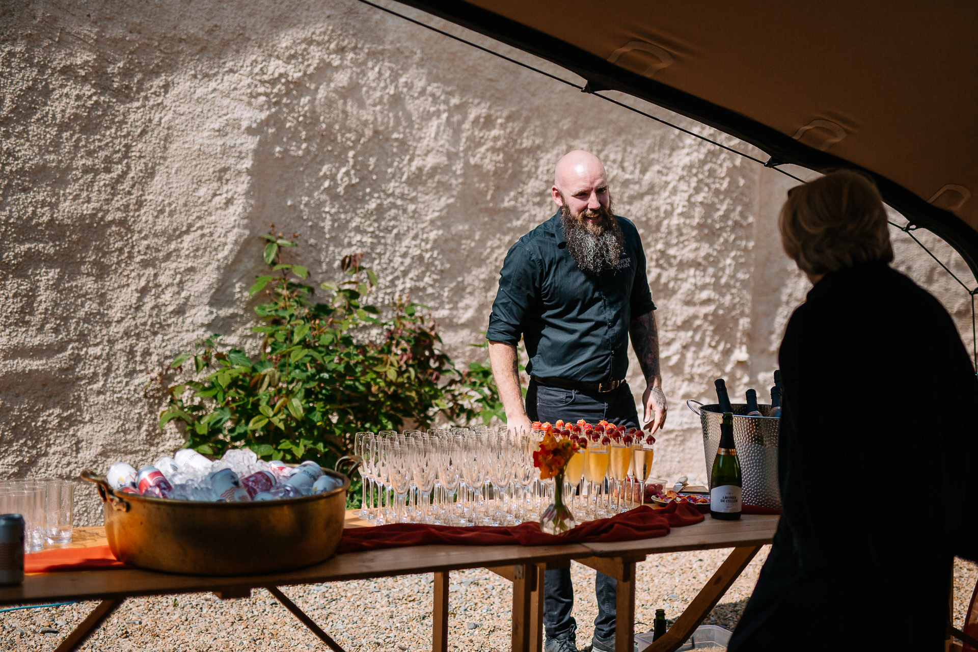 A man standing next to a table with a plant and a woman sitting