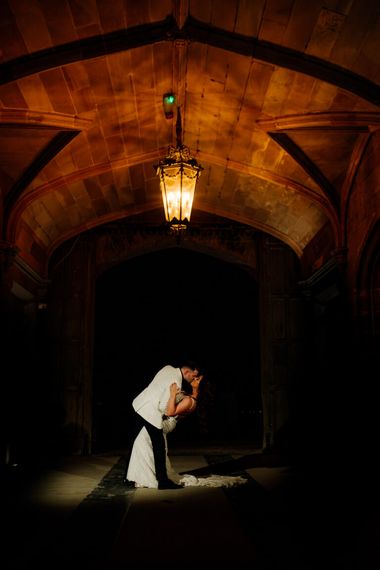 A man and woman kissing in a dark room with a chandelier