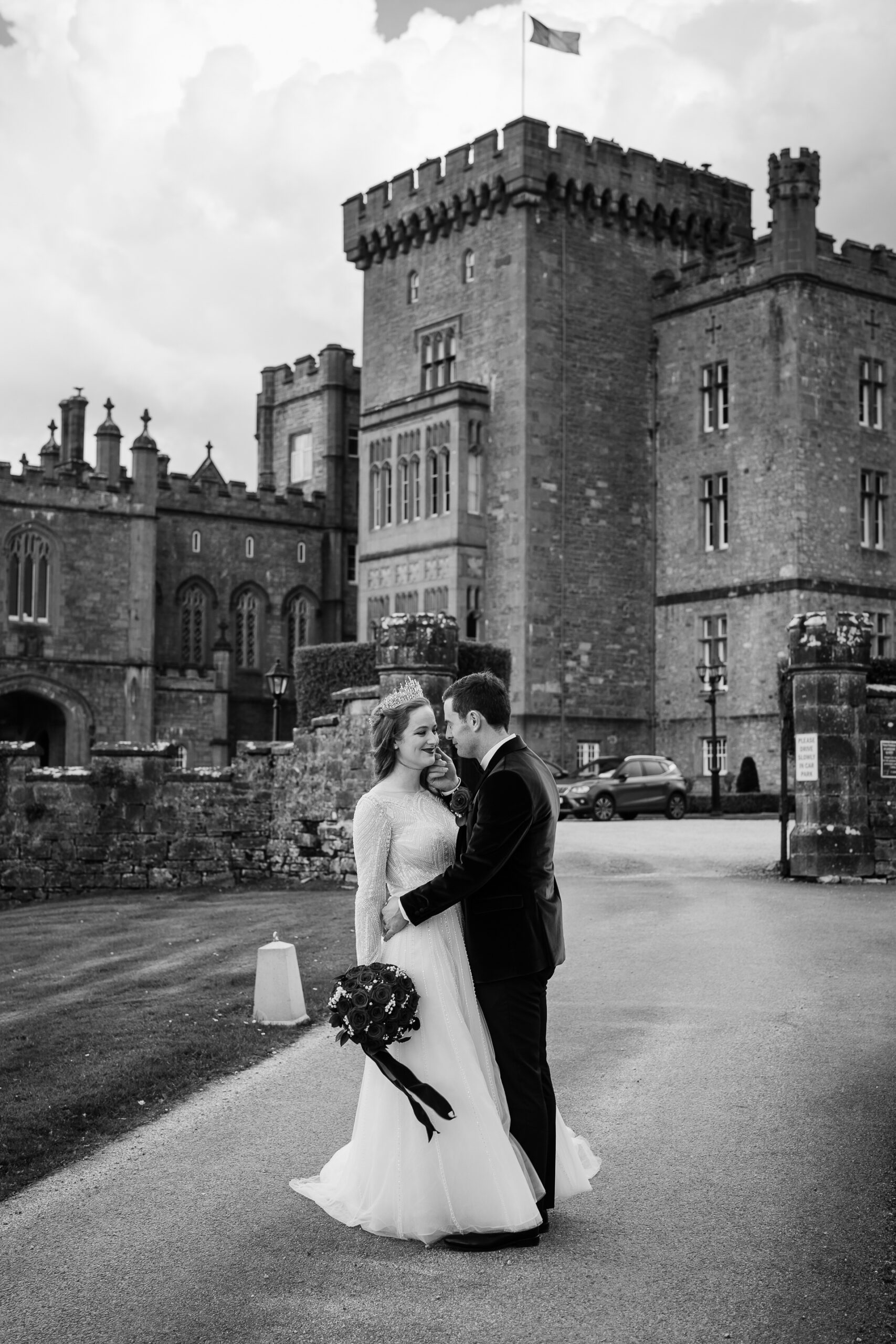 A man and woman kissing in front of a castle