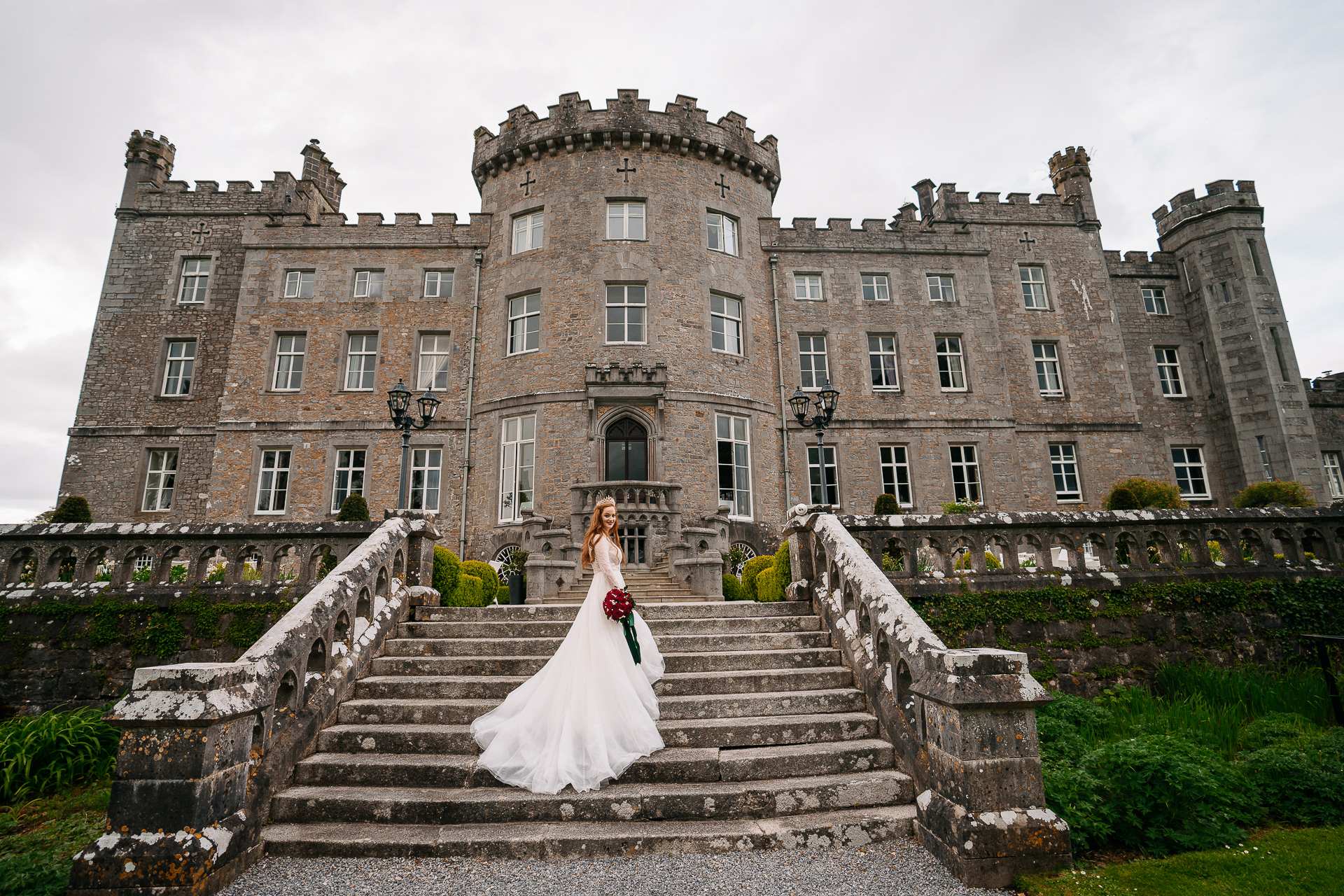 A person in a white dress standing on stairs in front of a large building