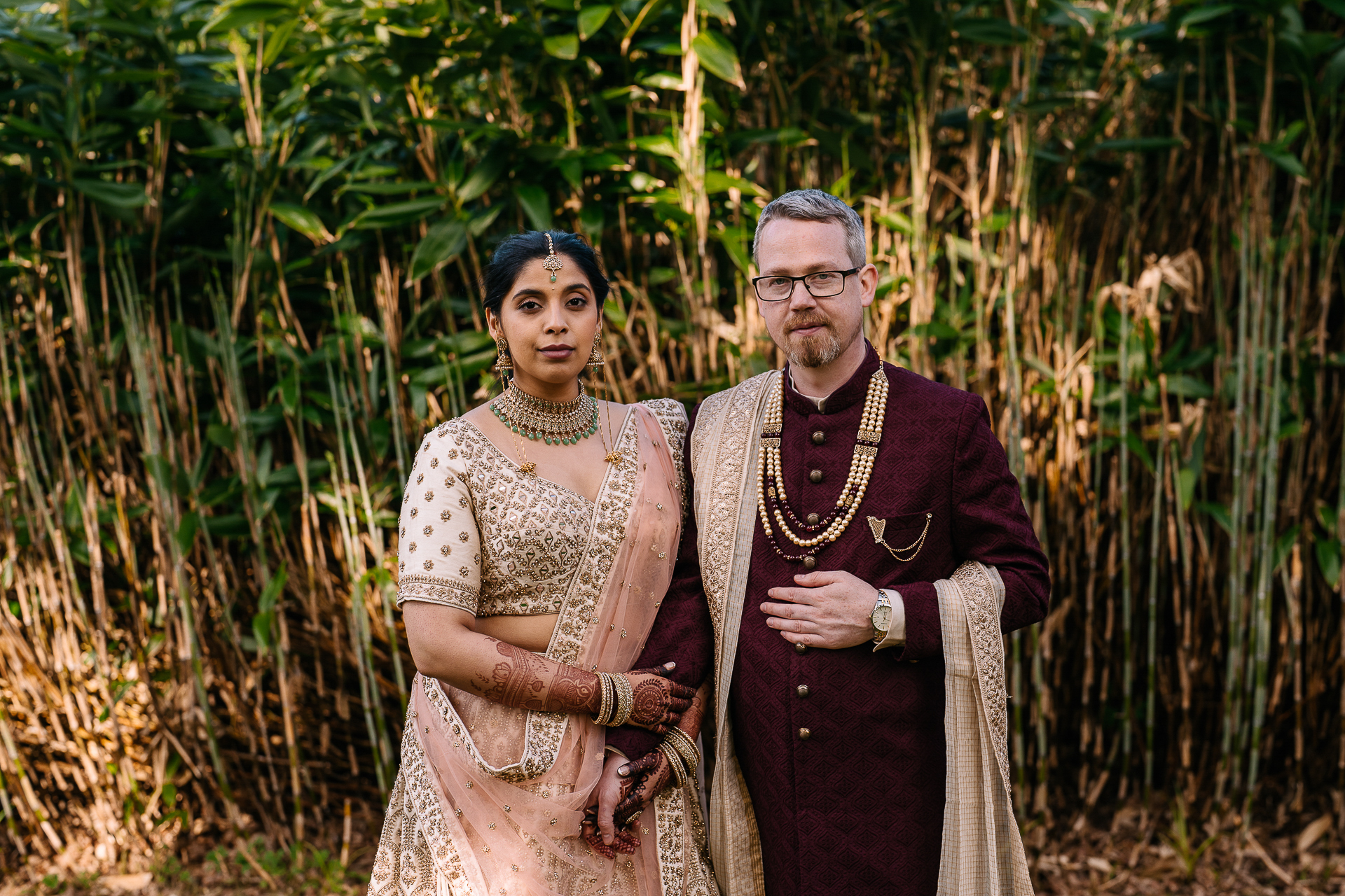 A man and woman posing for a picture in front of tall grass