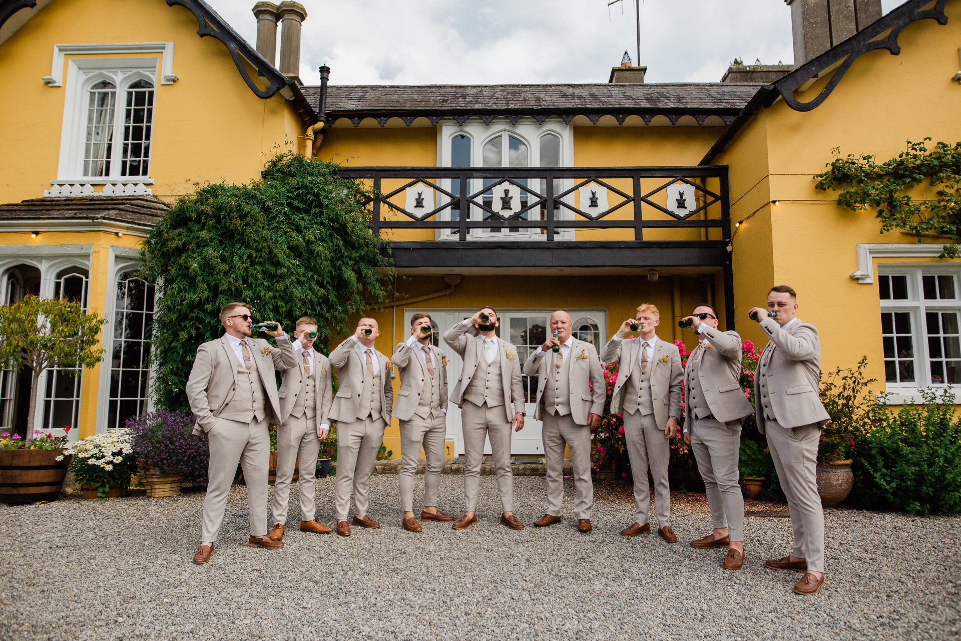 A group of men in white suits standing in front of a yellow building