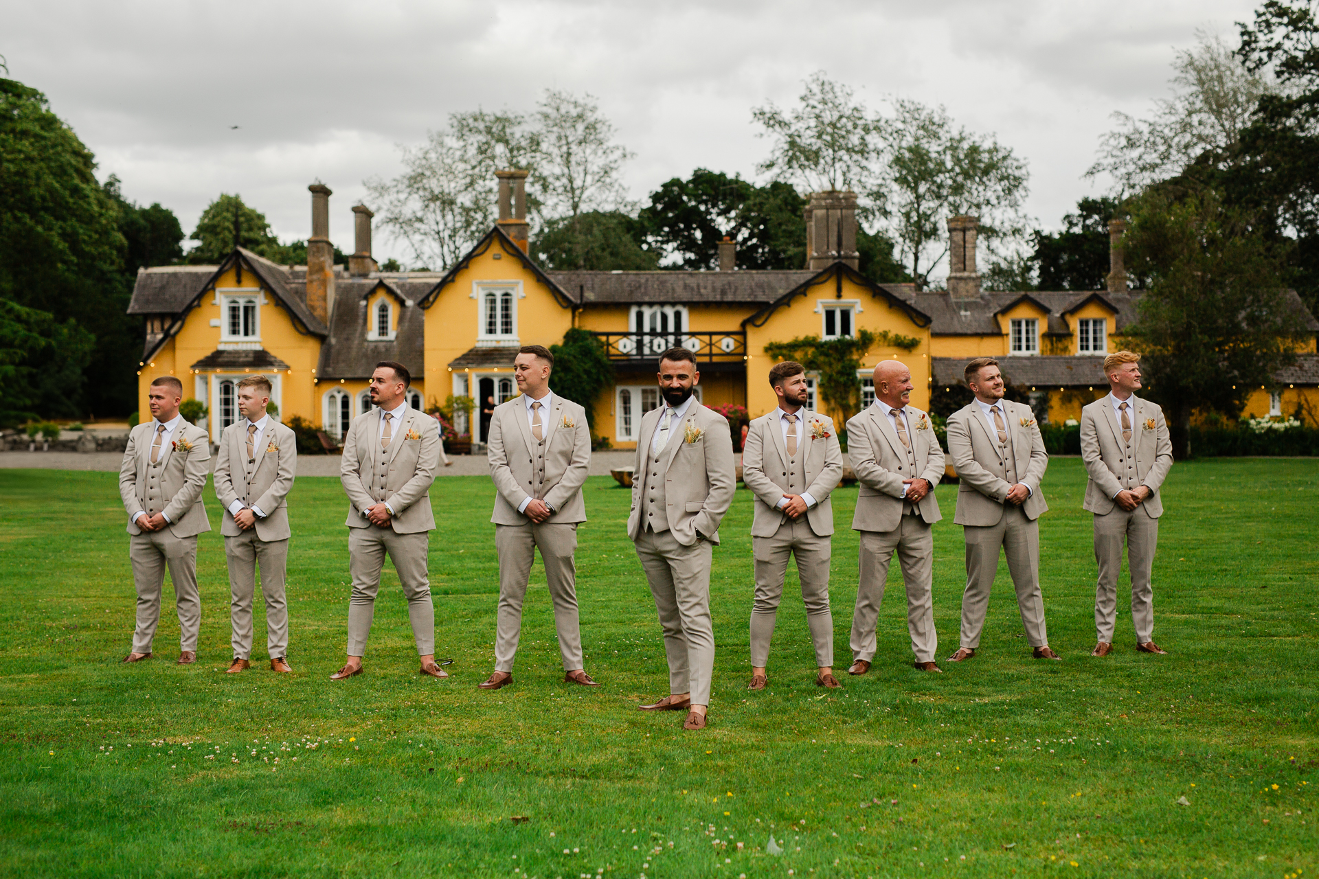 A group of men in suits standing in a field in front of a house