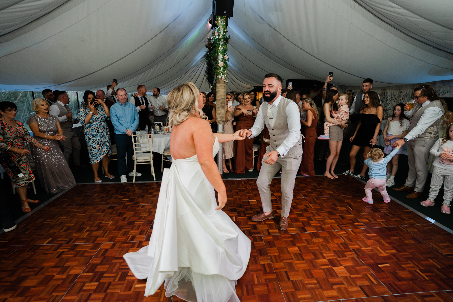 A man and woman dancing in a tent with a crowd watching