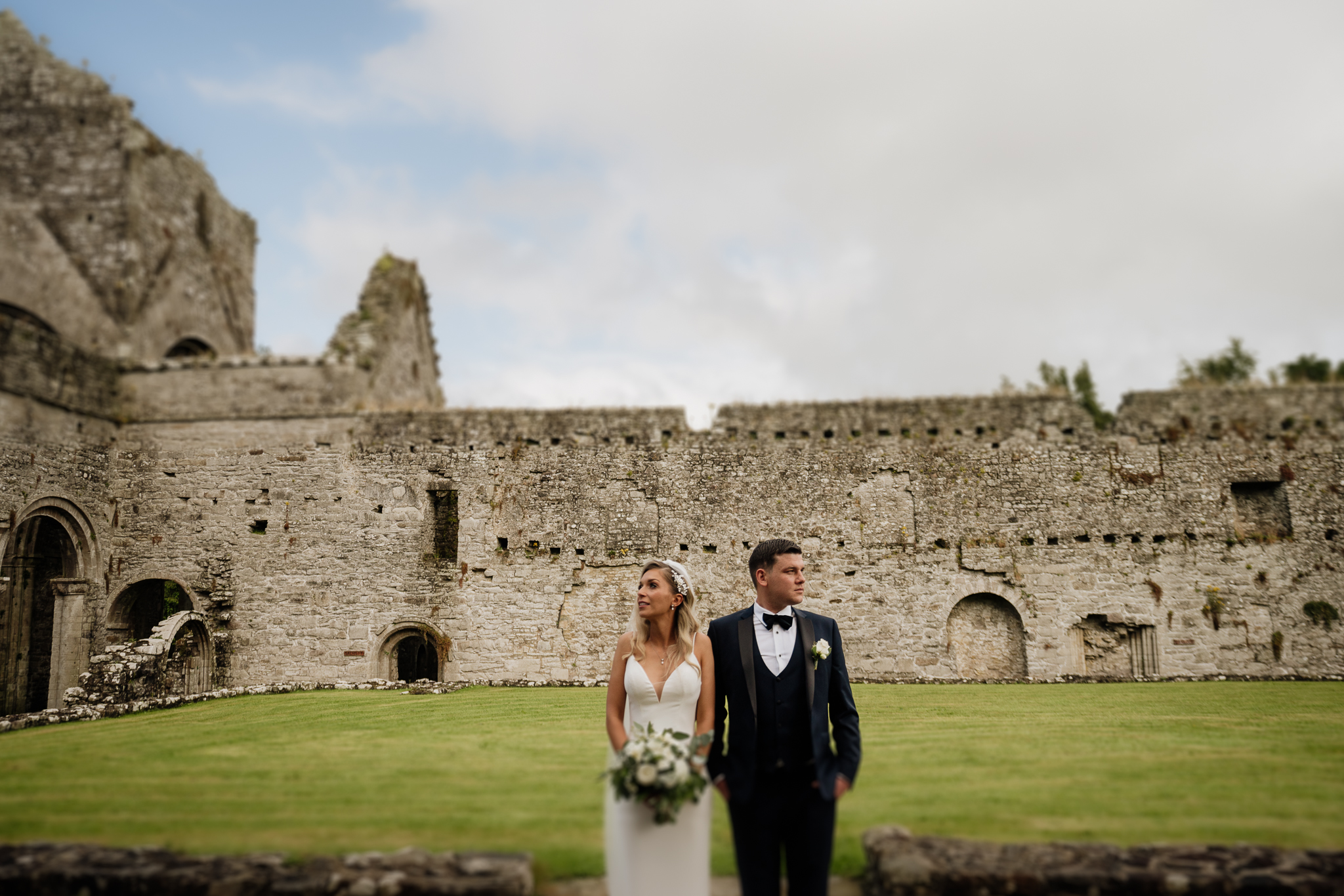 A man and woman posing in front of a stone building