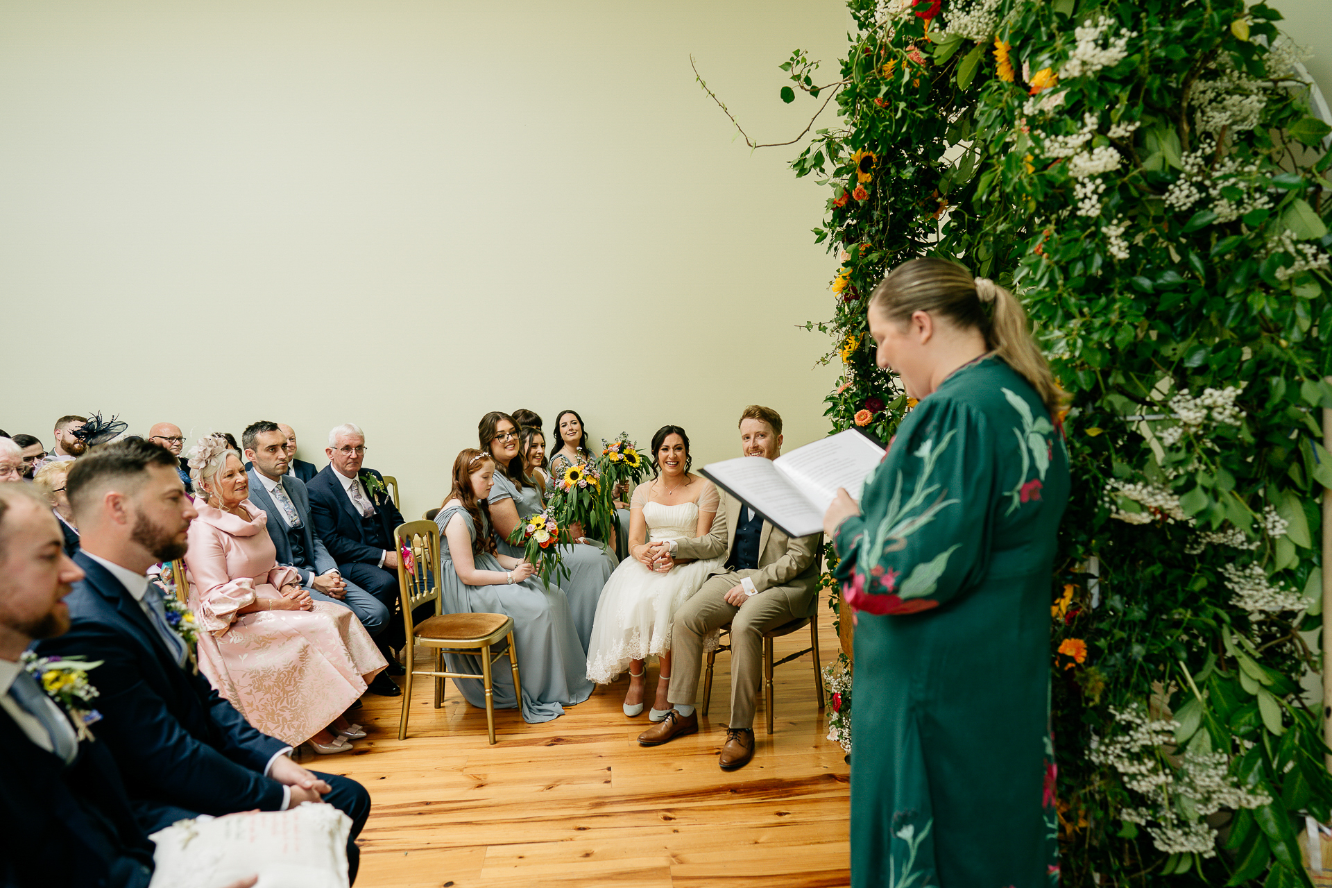 A man in a green dress standing in front of a group of people