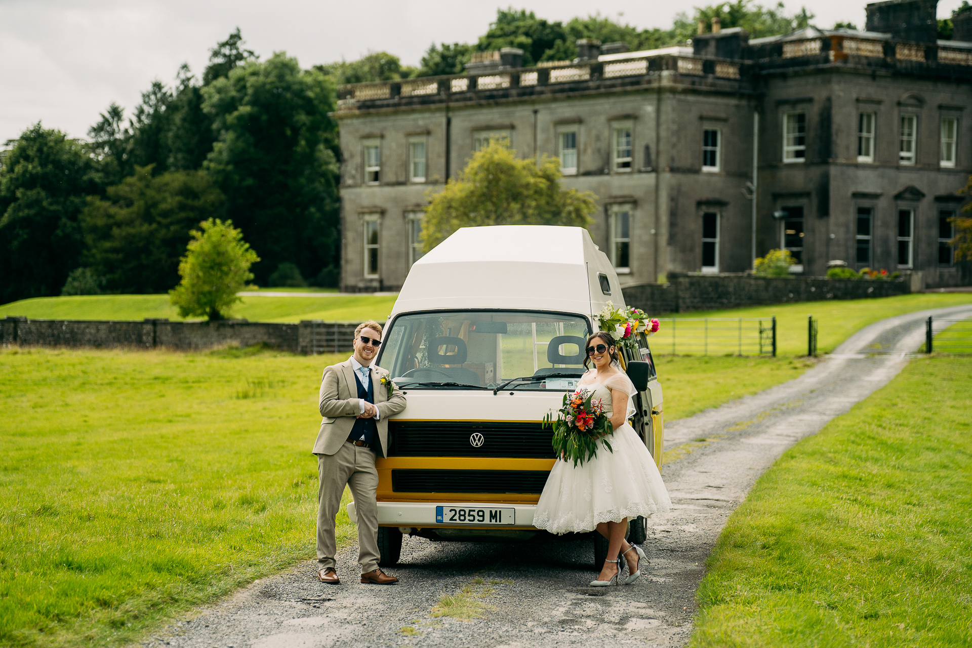 A man and woman in wedding attire standing next to a car