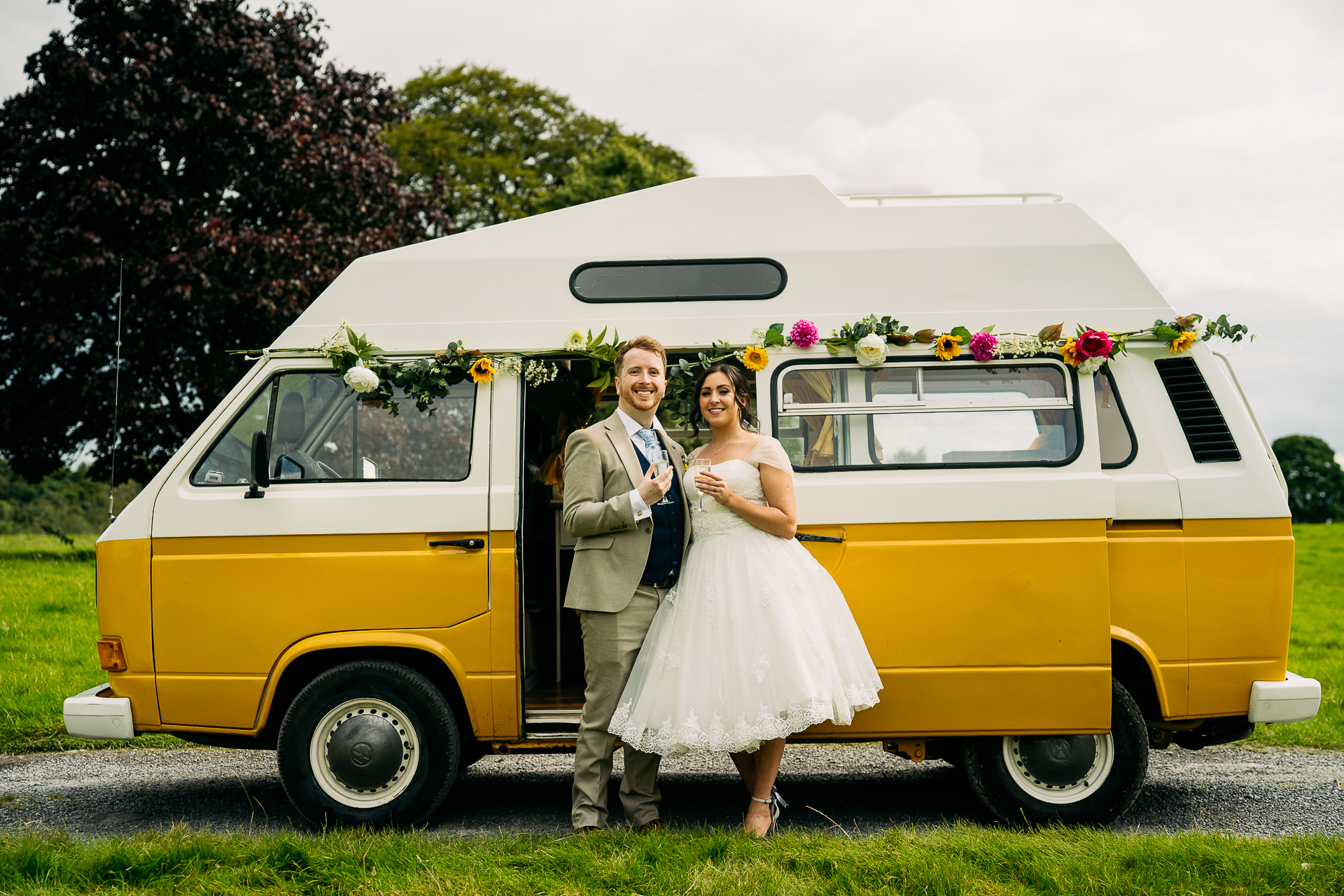 A bride and groom posing in front of a yellow van