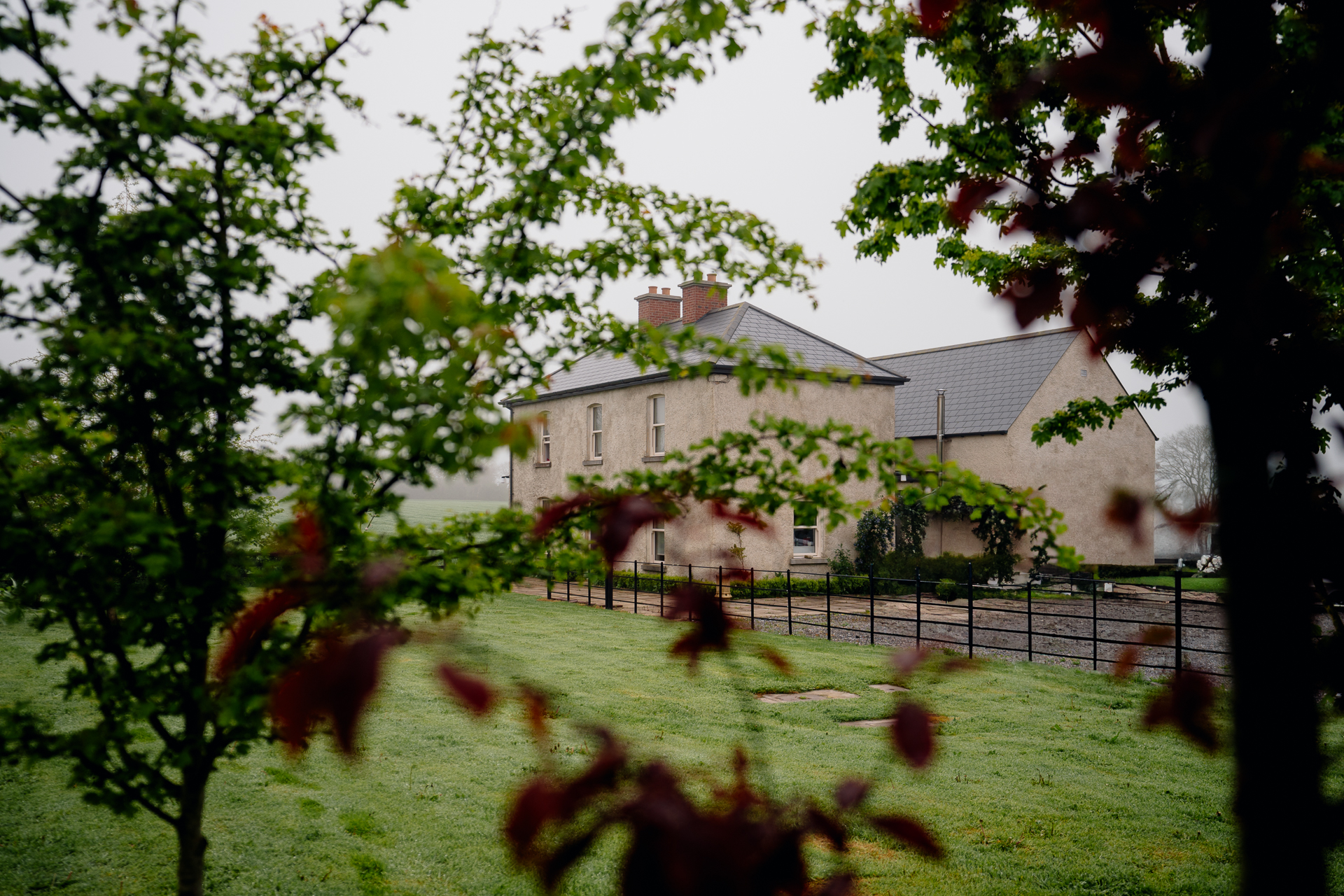 A large house with a fence and trees in front of it