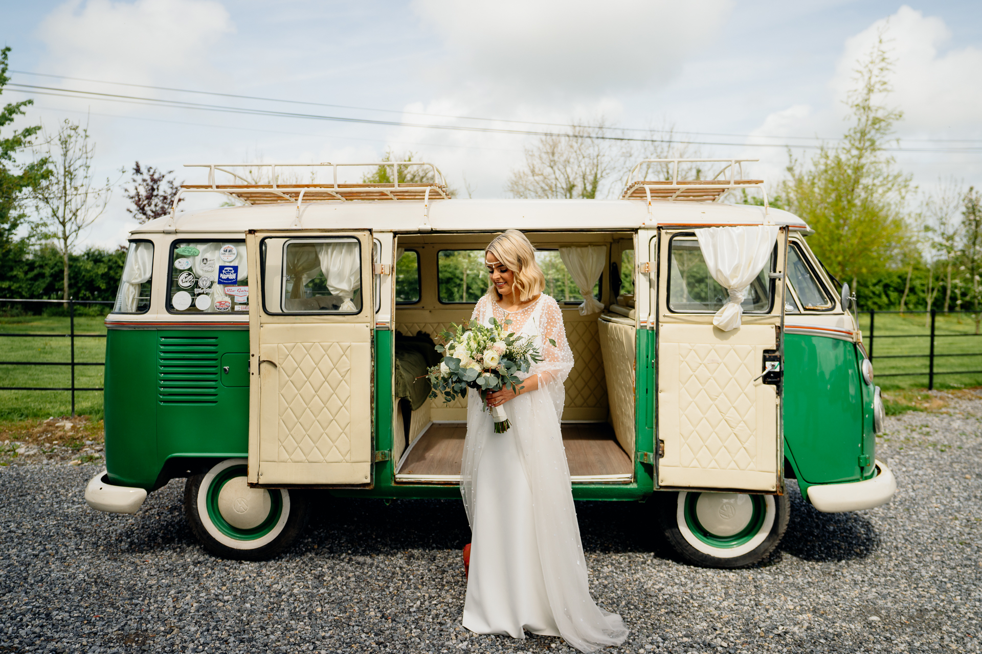 A person in a white dress standing next to a green and white van