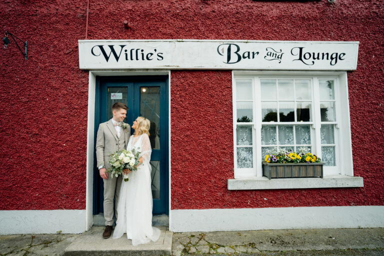 A man and woman in wedding attire standing in front of a building