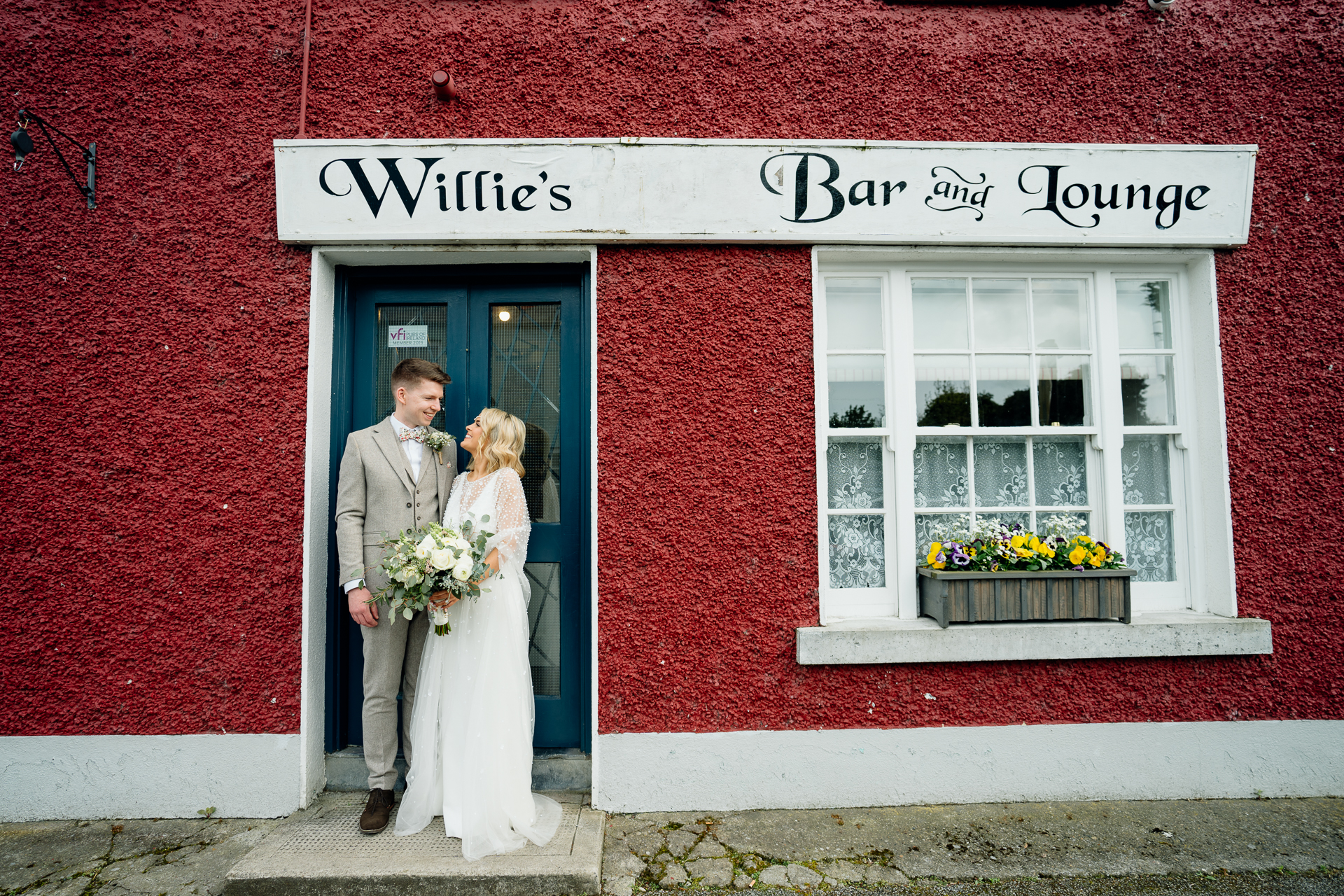 A man and woman in wedding attire standing in front of a building