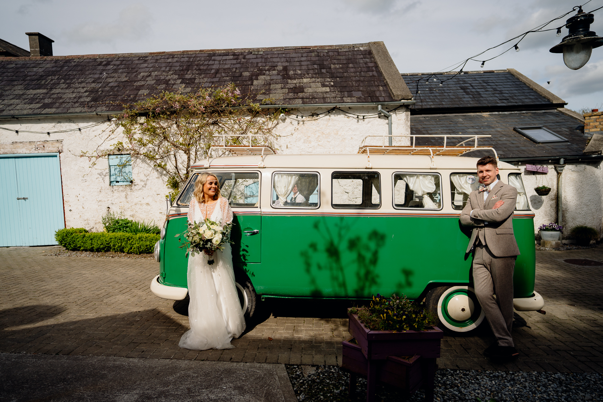 A bride and groom posing in front of a van