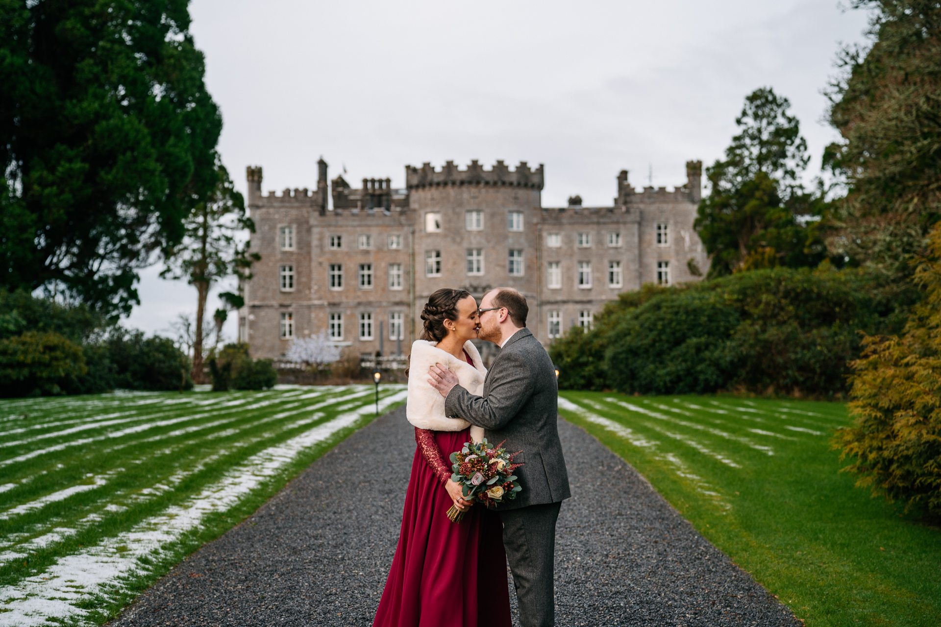 A man and woman kissing in front of a large building