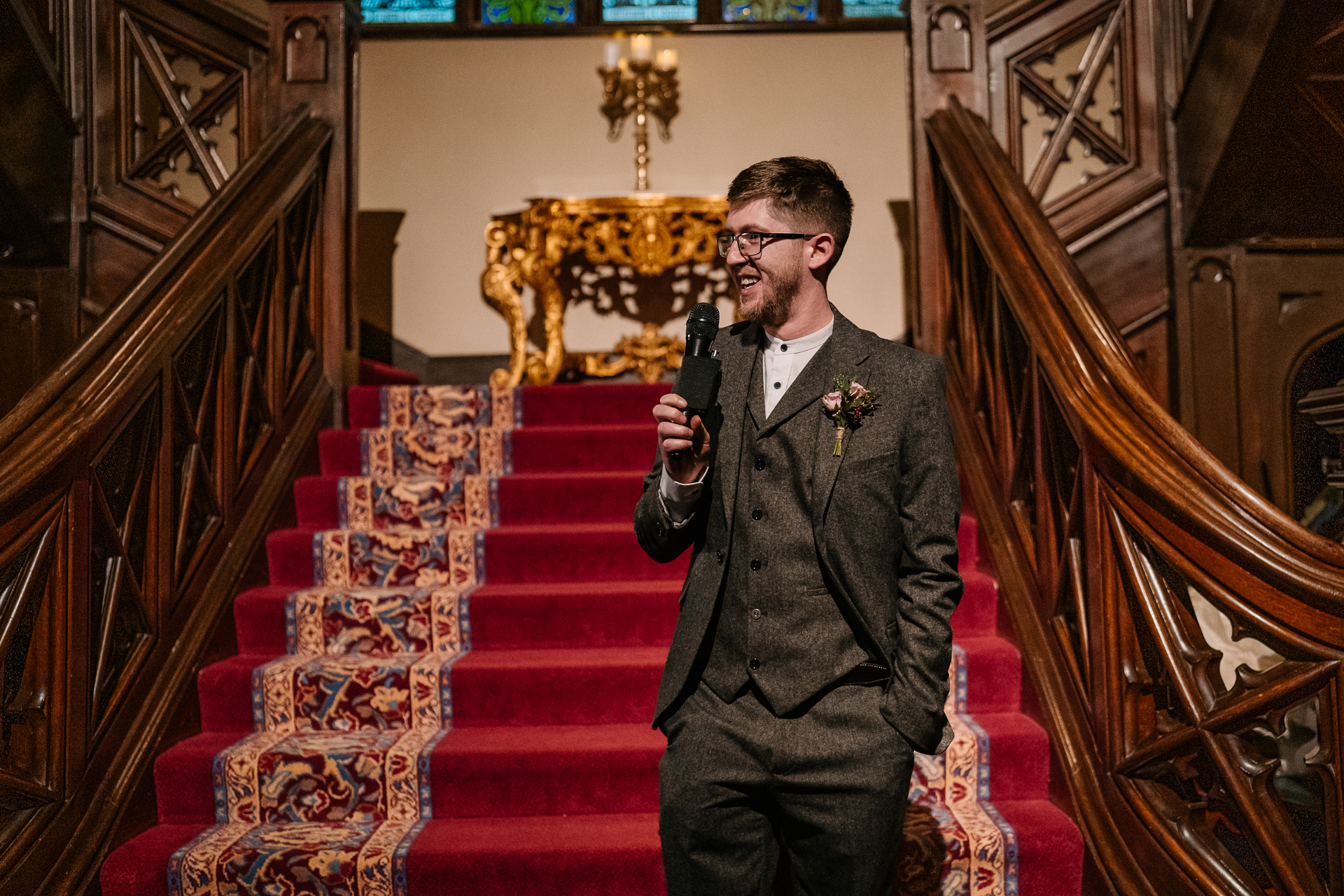 A person in a suit holding a microphone and standing on a staircase