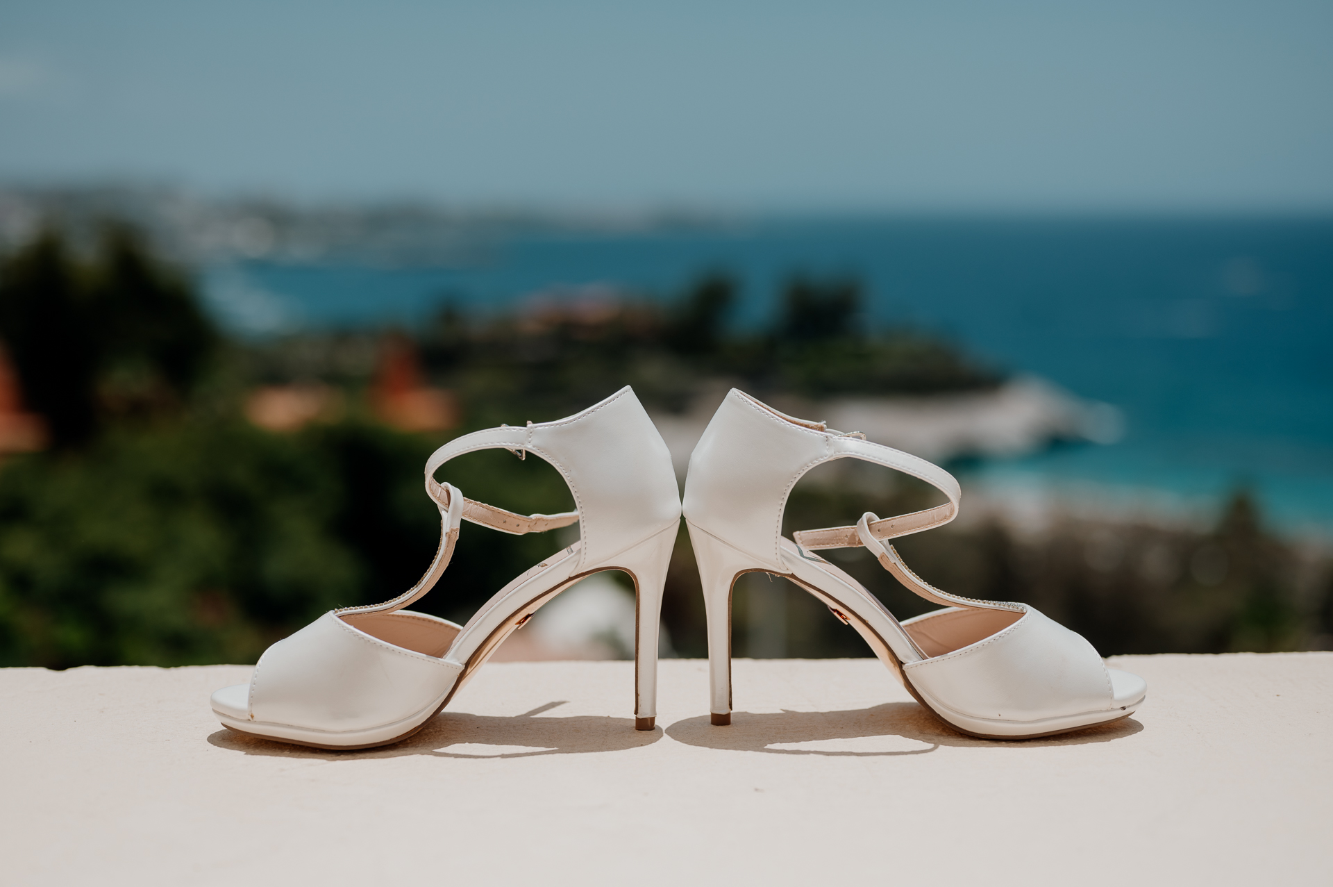 A pair of white sandals on a table overlooking a body of water