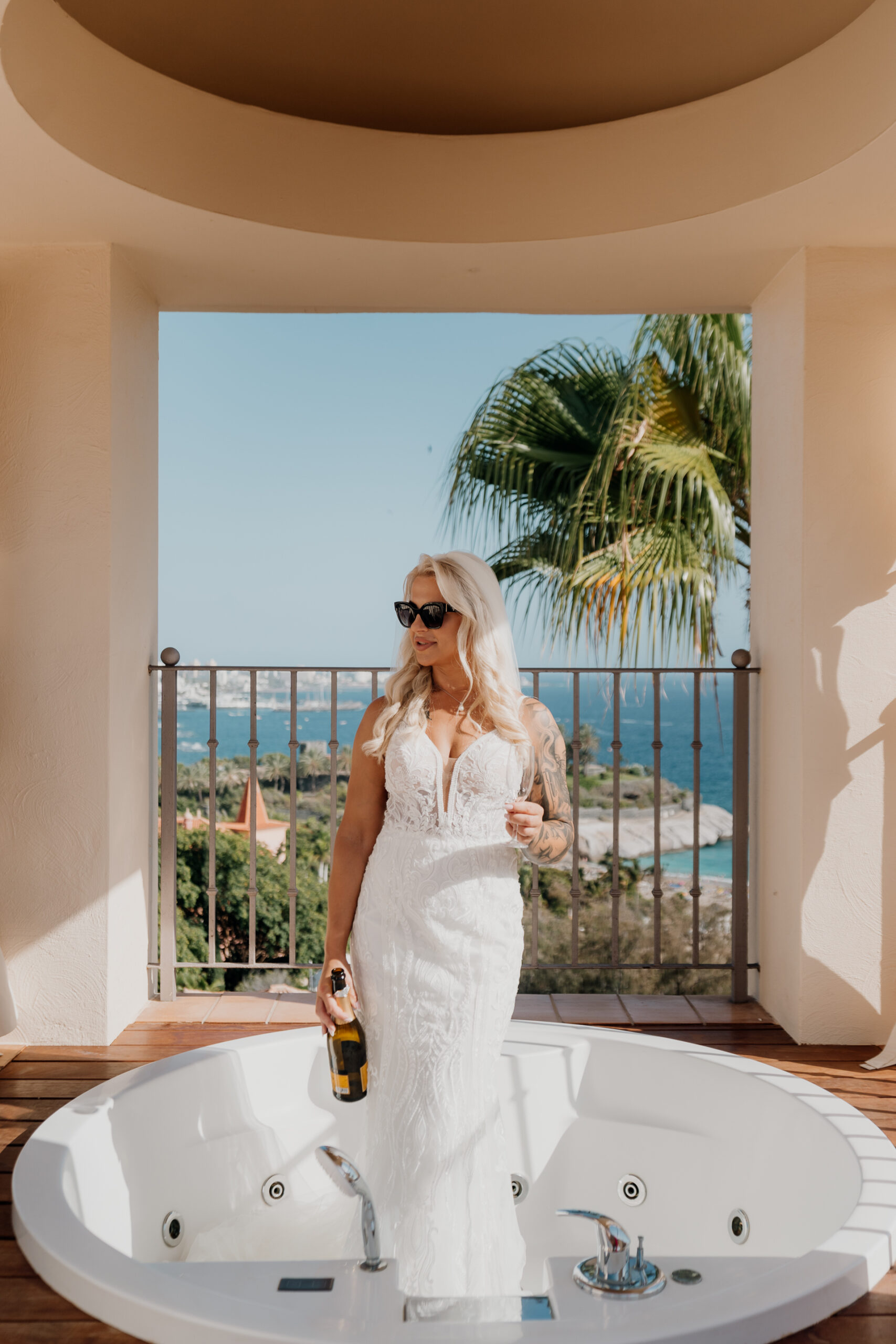 A person in a white dress holding a bottle and standing in a bathtub