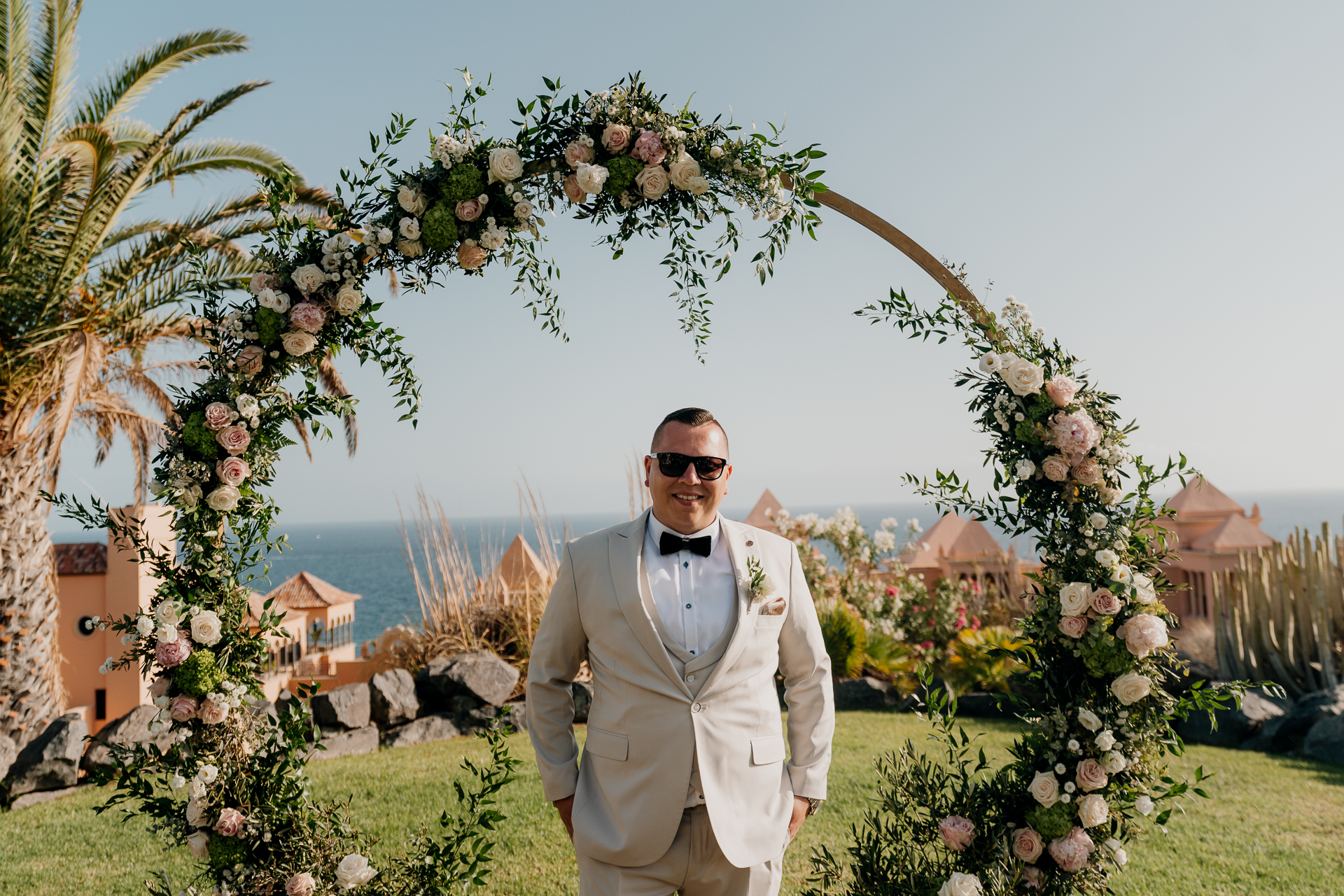 A man in a suit standing in front of a flowering tree