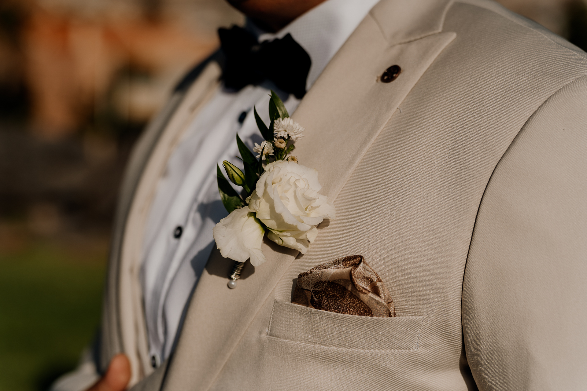 A person wearing a white suit with a bouquet of flowers