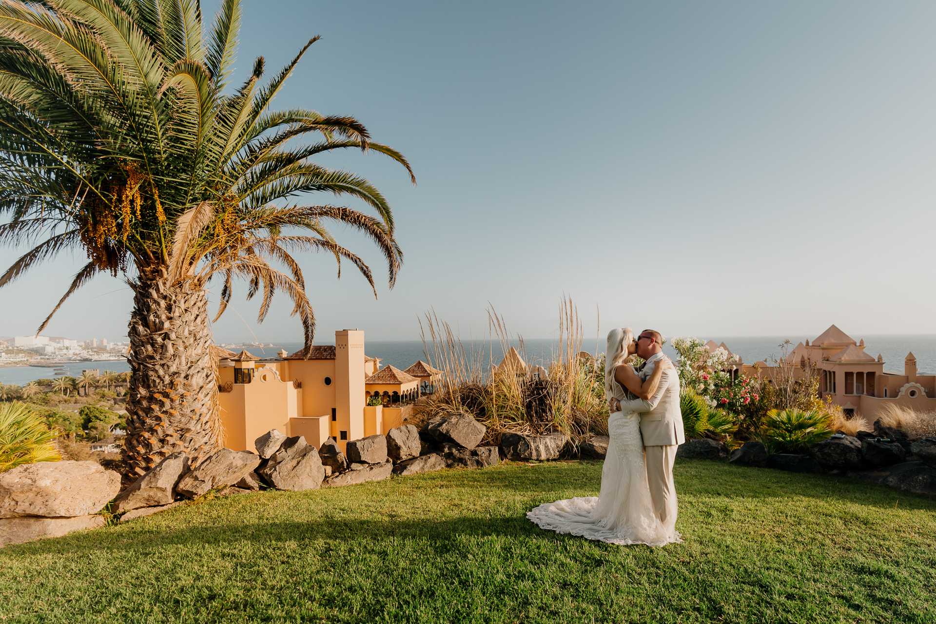 A man and woman in wedding attire standing in front of a palm tree