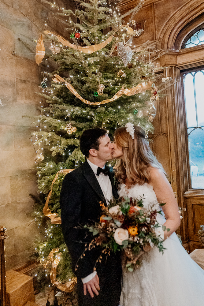 A man and woman kissing in front of a christmas tree