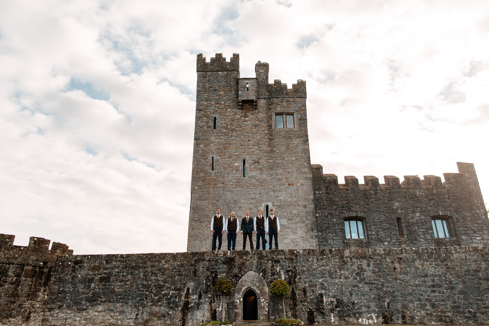 A group of people standing on a stone wall in front of a castle