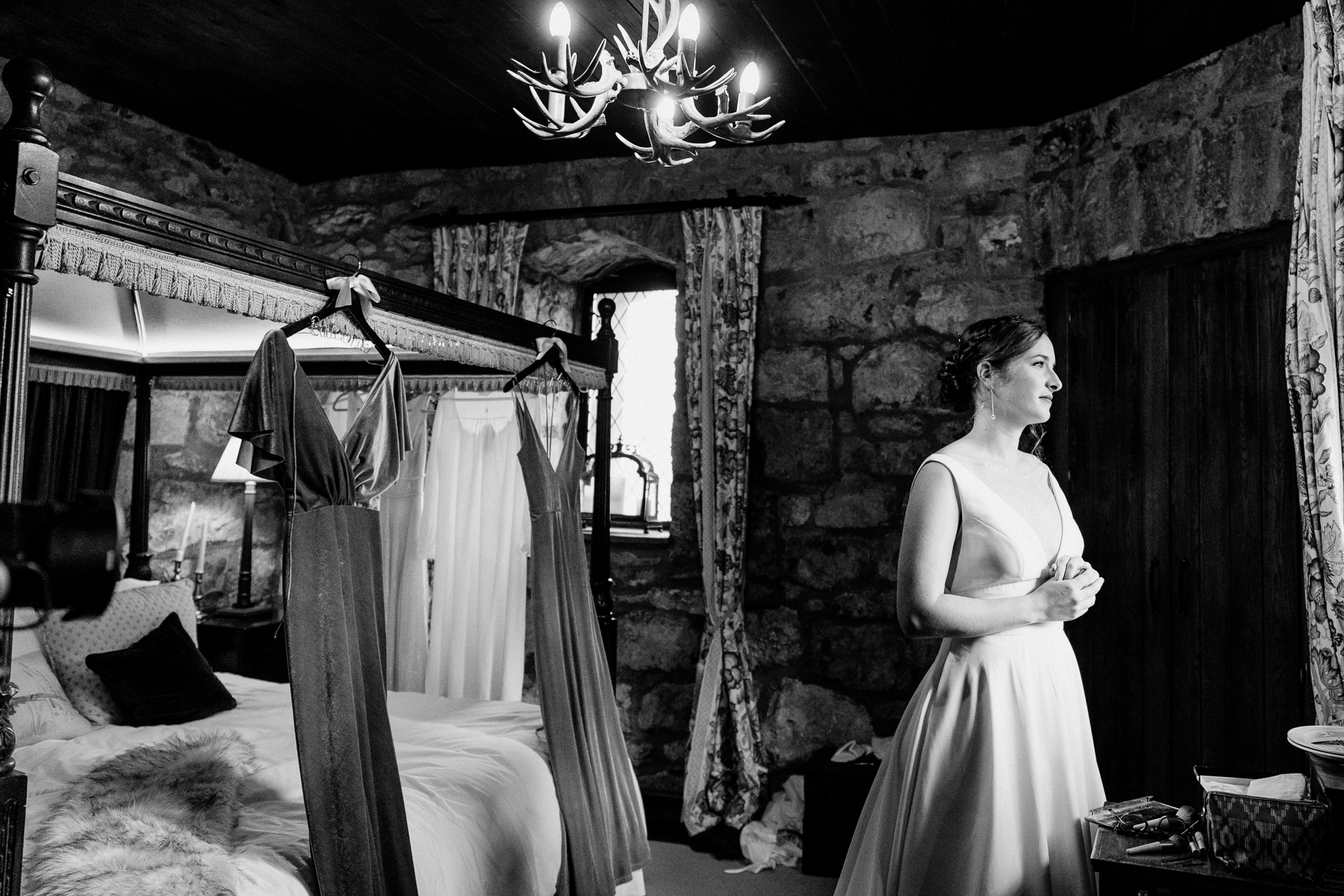 A person in a wedding dress in a room with a bed and a chandelier