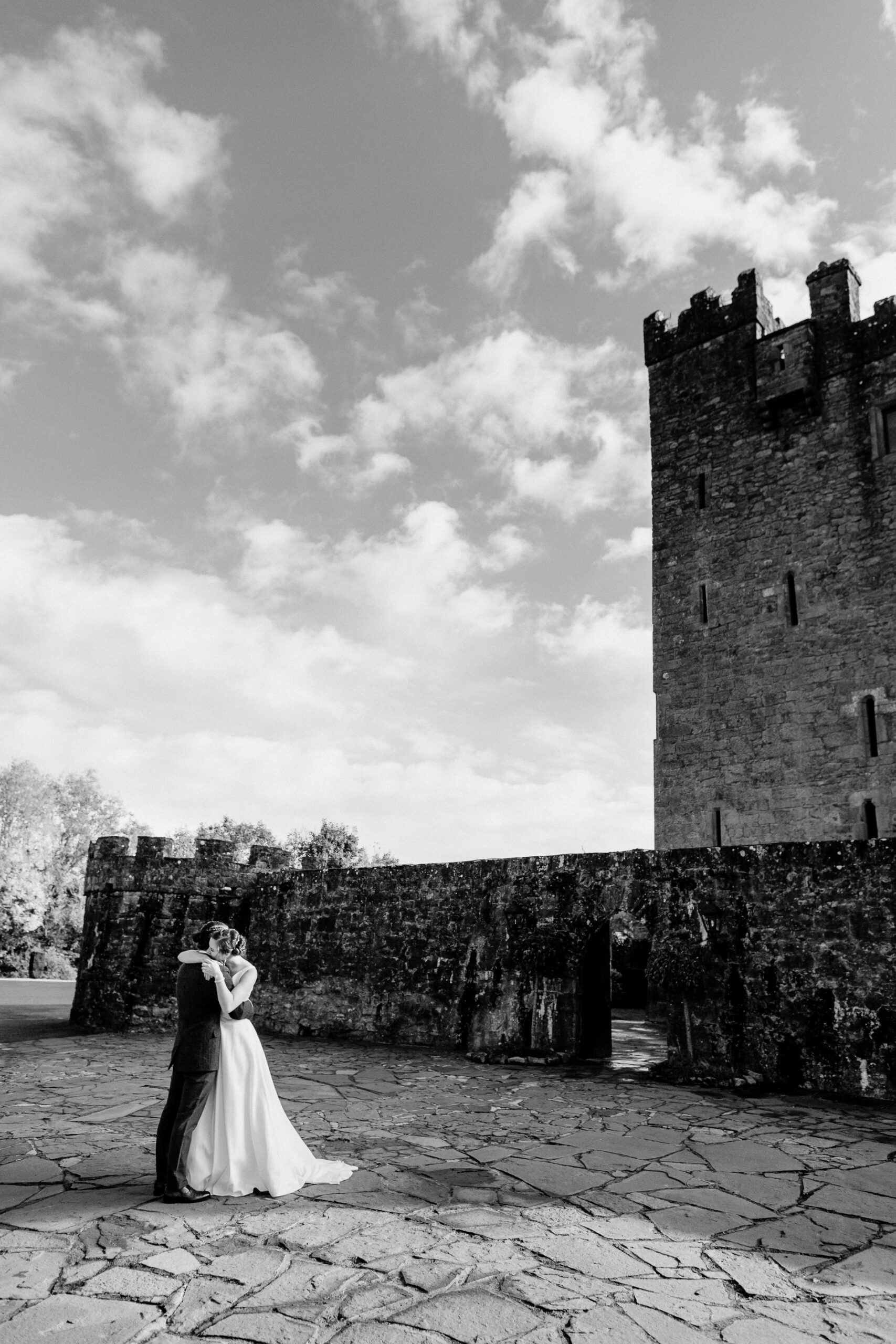 A man and woman kissing in front of a castle