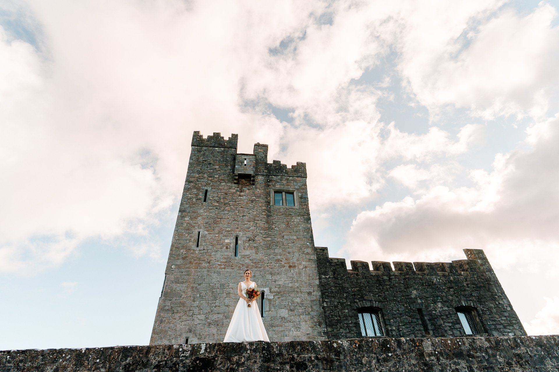 A bride and groom in front of a castle