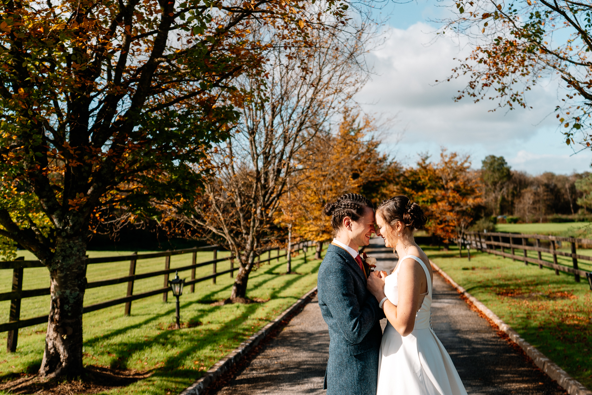 A man and woman kissing on a path with trees and grass