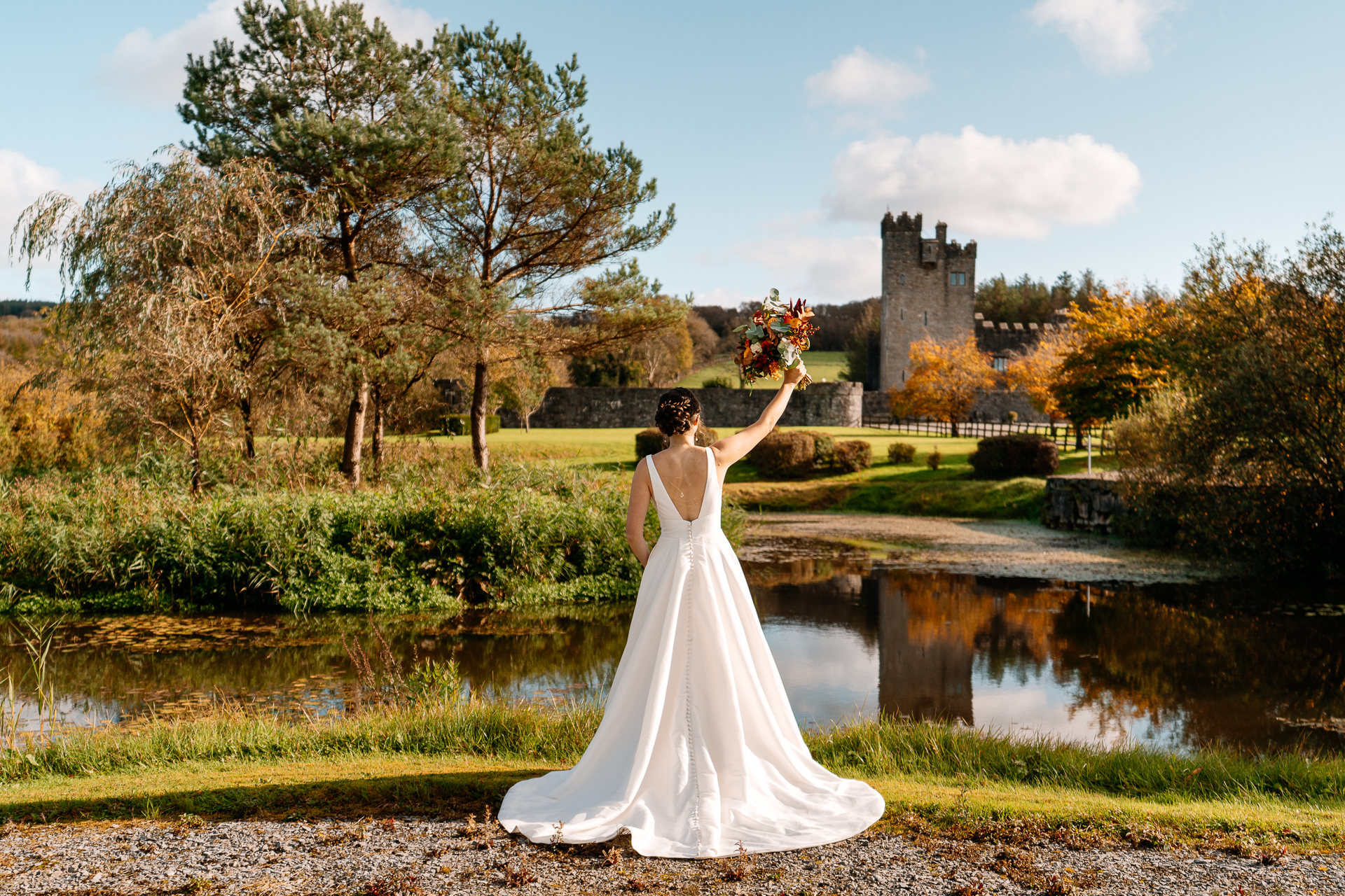 A person in a white dress holding flowers by a pond