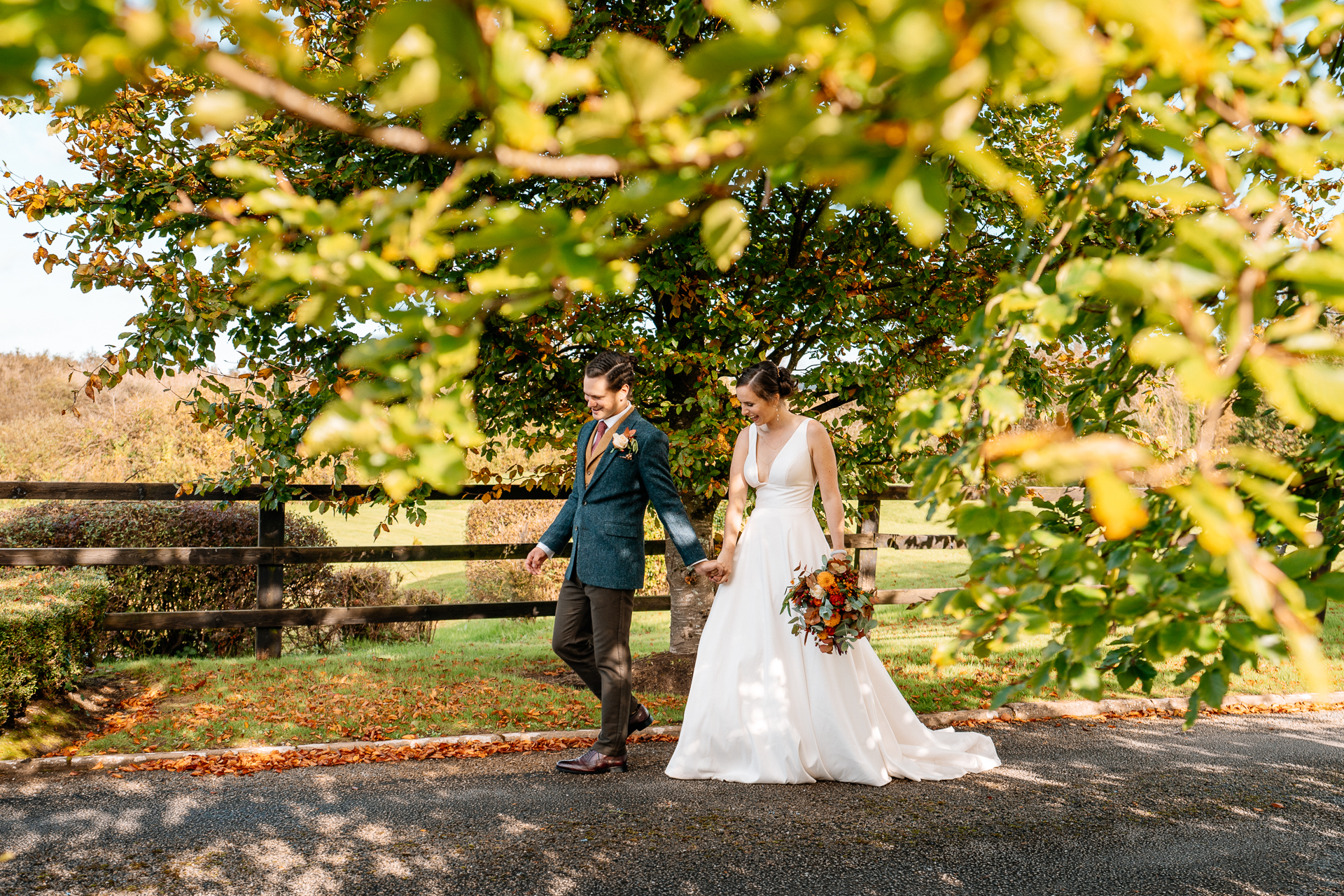 A man and woman walking down a road with a tree and grass