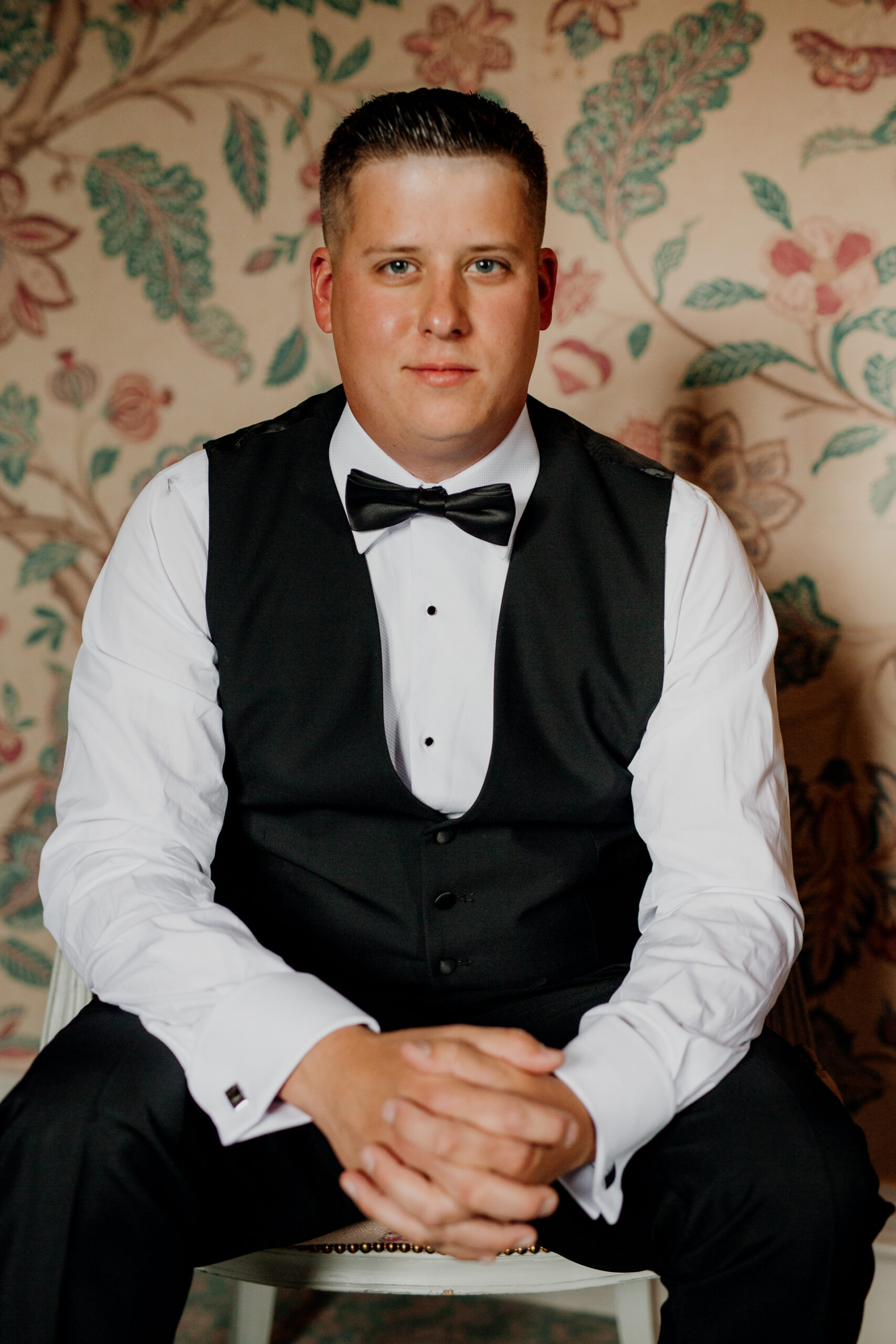 A man in a tuxedo sitting on a chair