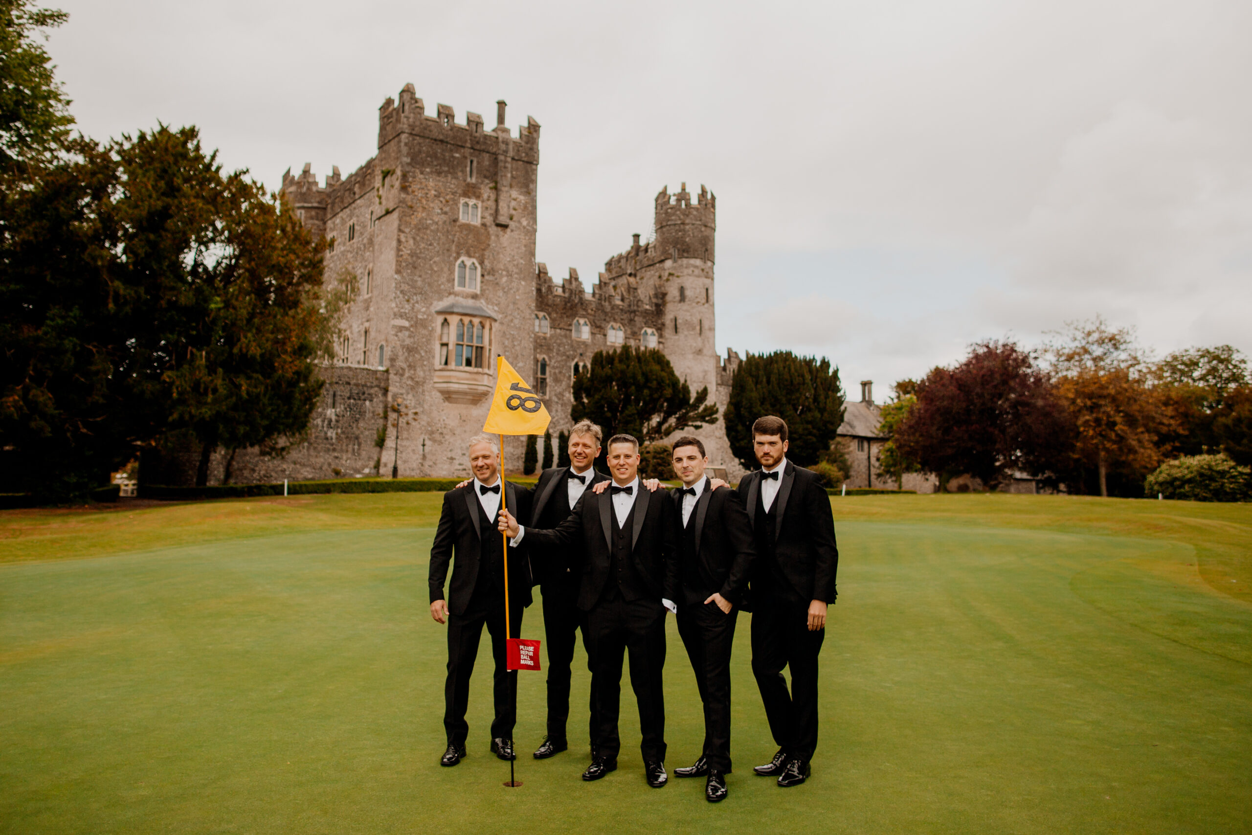 A group of men in suits holding flags in front of a castle