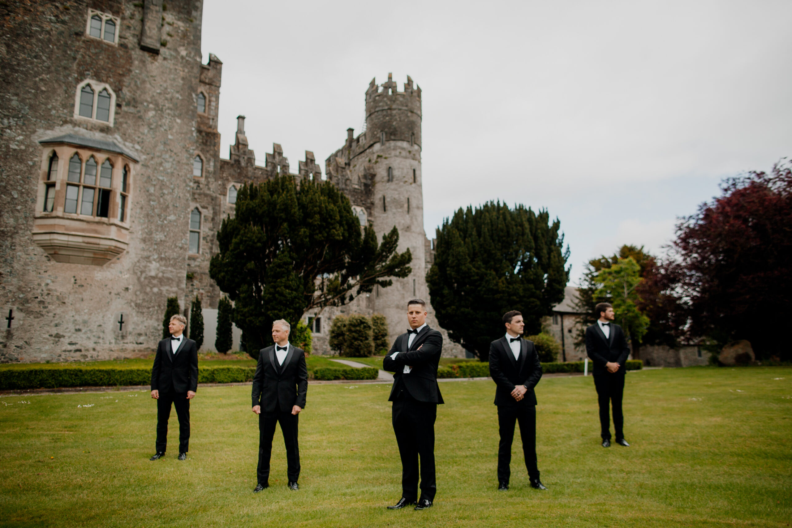 A group of men in suits standing in front of a castle