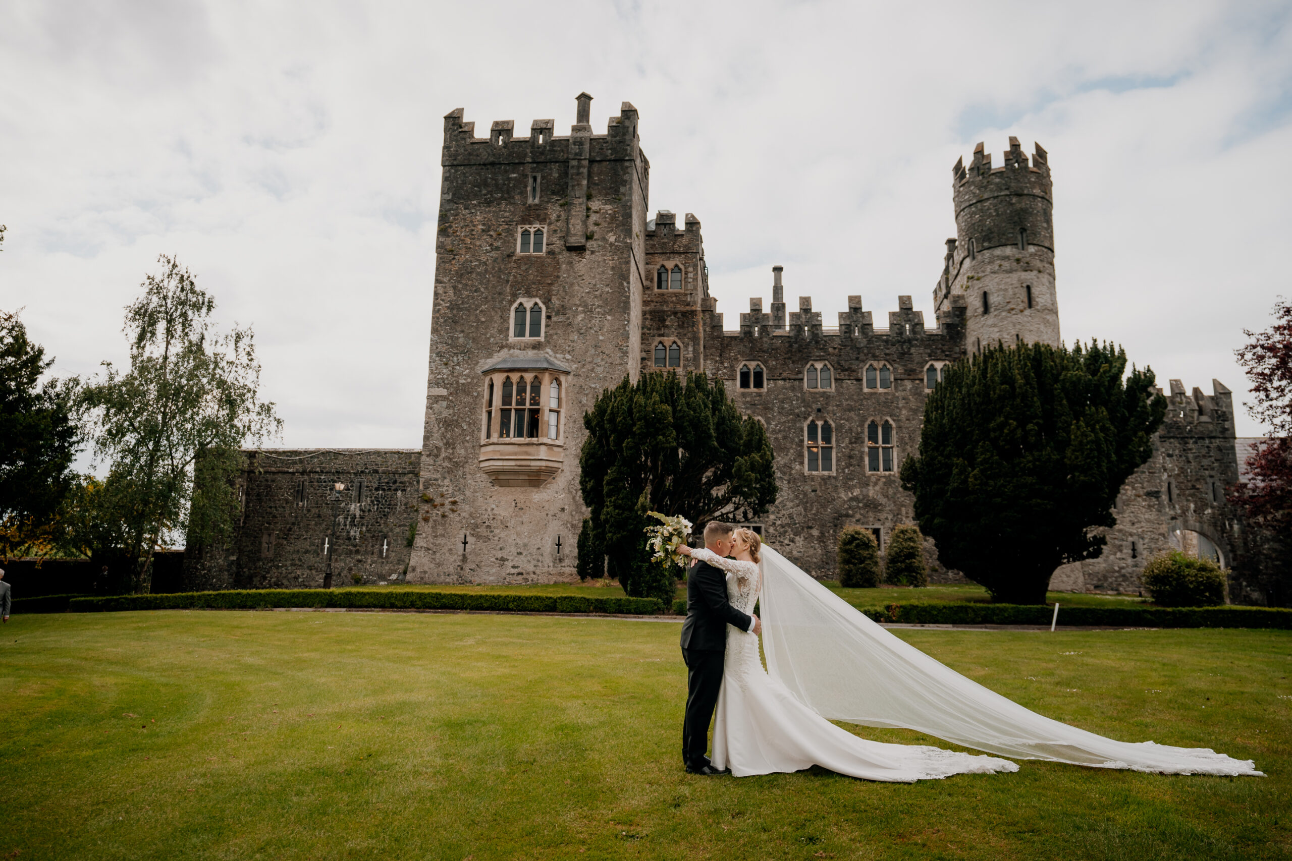 A man and woman kissing in front of a castle