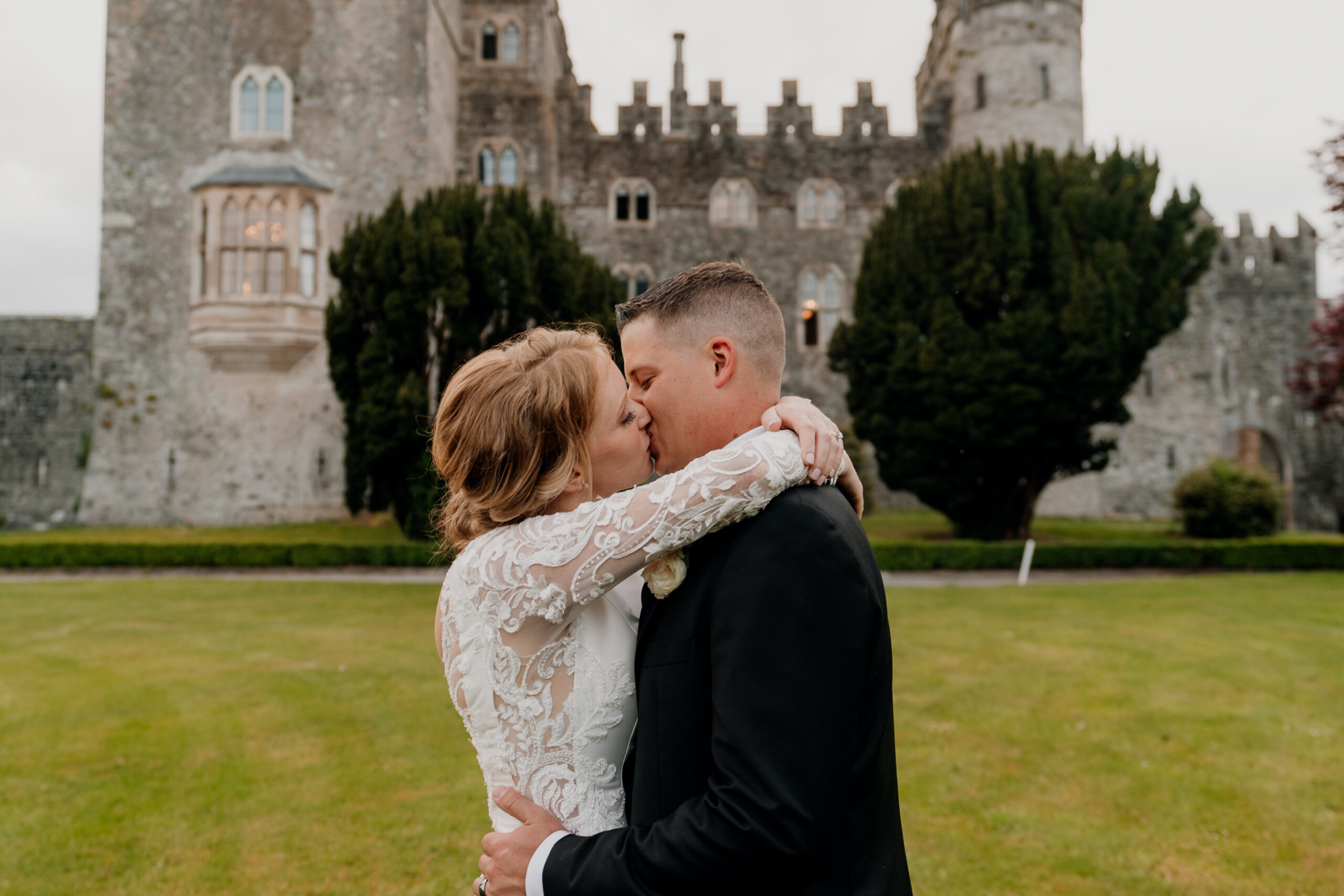 A man and woman kissing in front of a castle