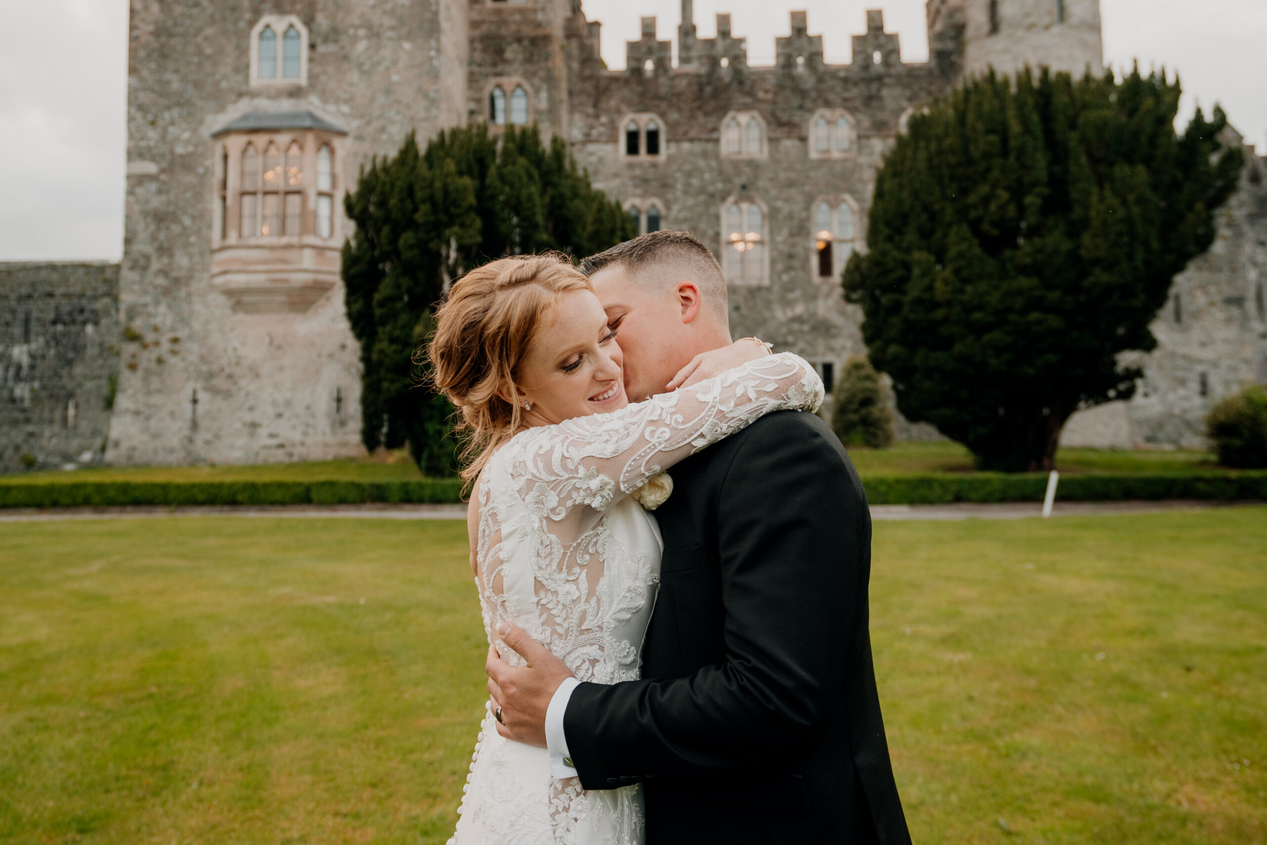 A man and woman kissing in front of a castle