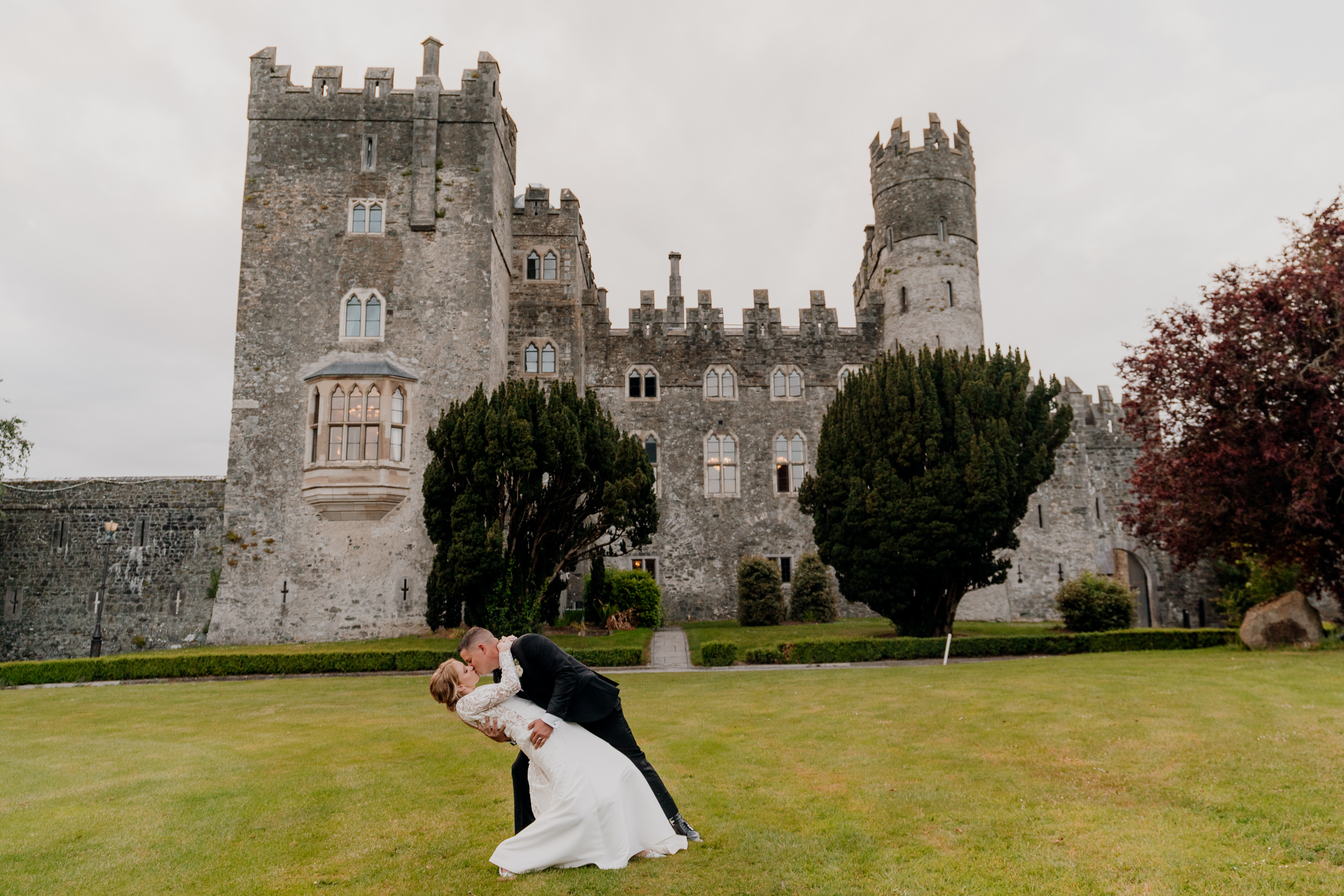 A man and woman kissing in front of a castle