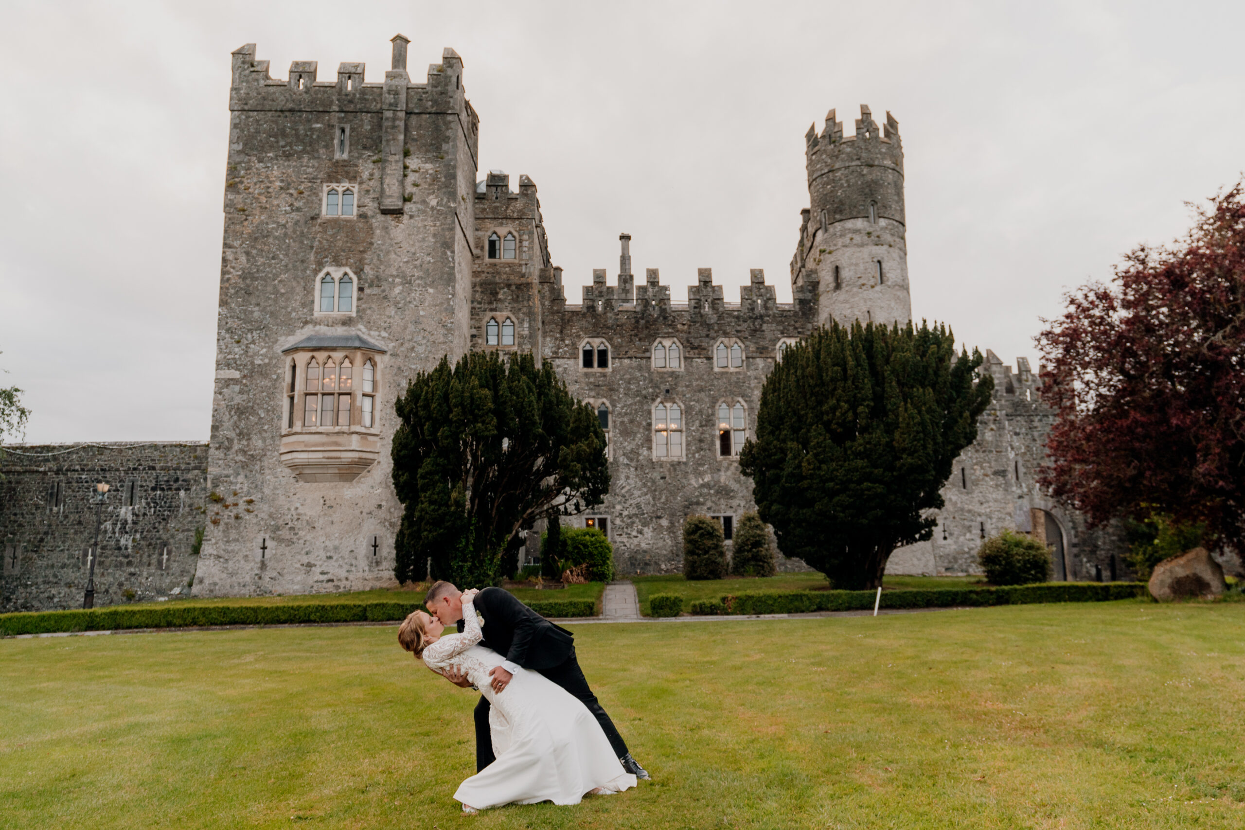 A man and woman kissing in front of a castle