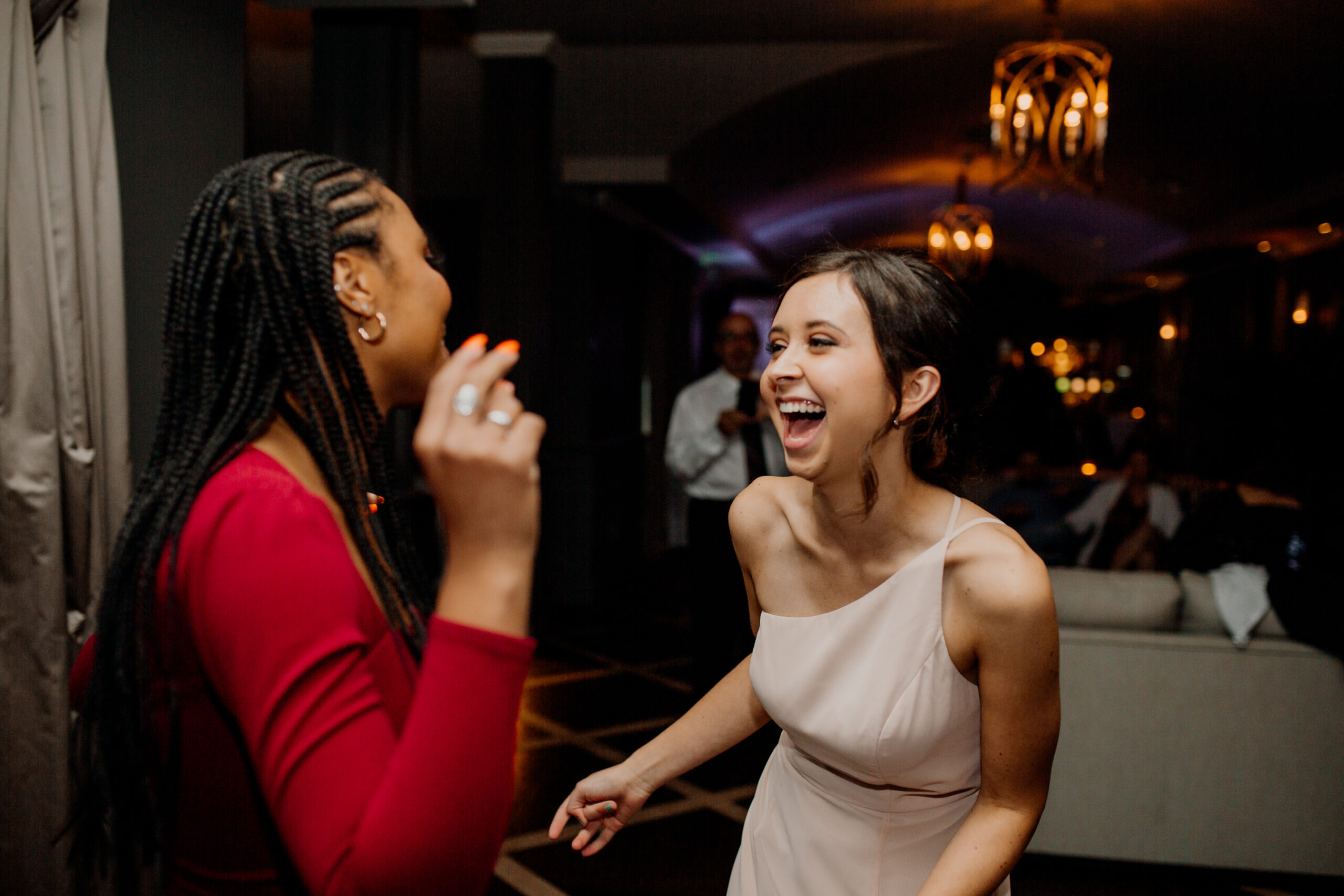 A woman in a white dress laughing at another woman in a red dress