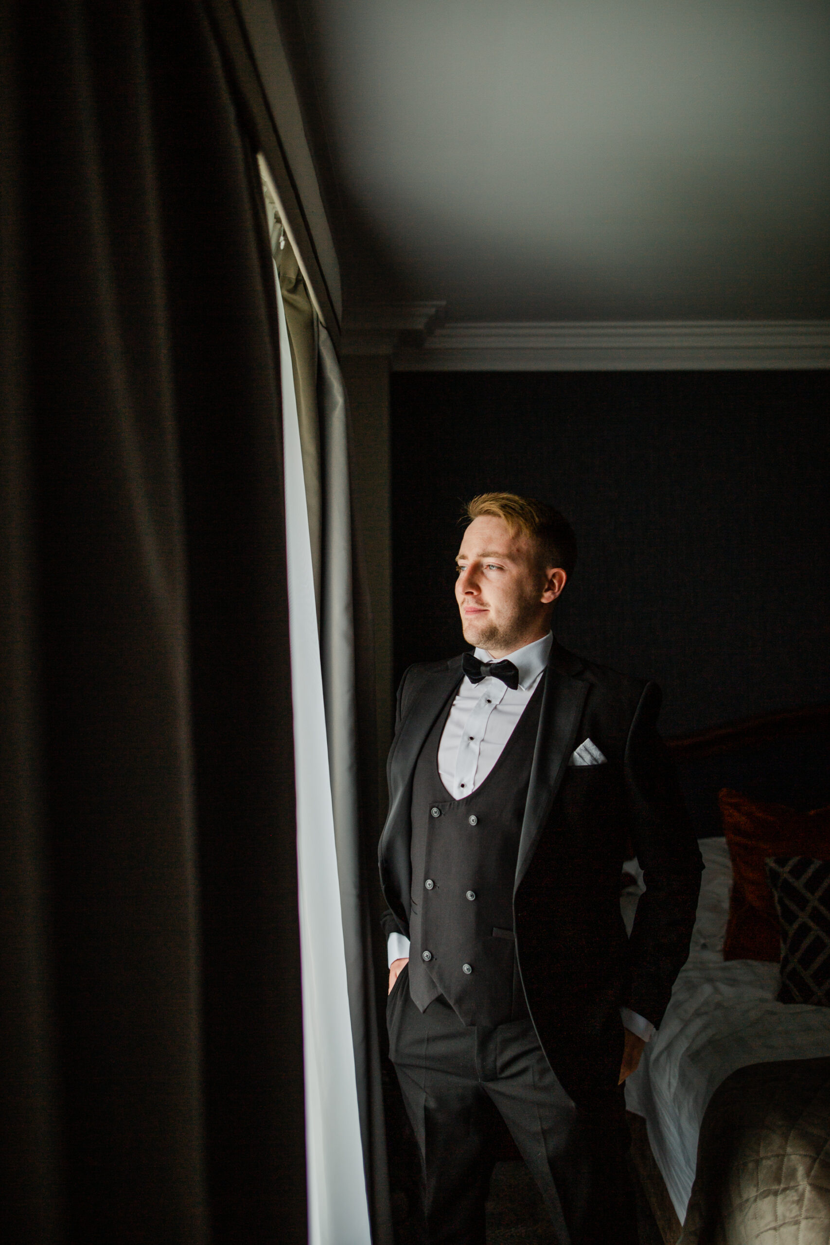 A man in a suit and bow tie standing in a room