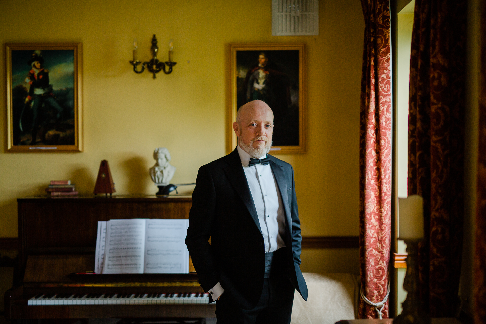 A man in a suit standing in front of a piano