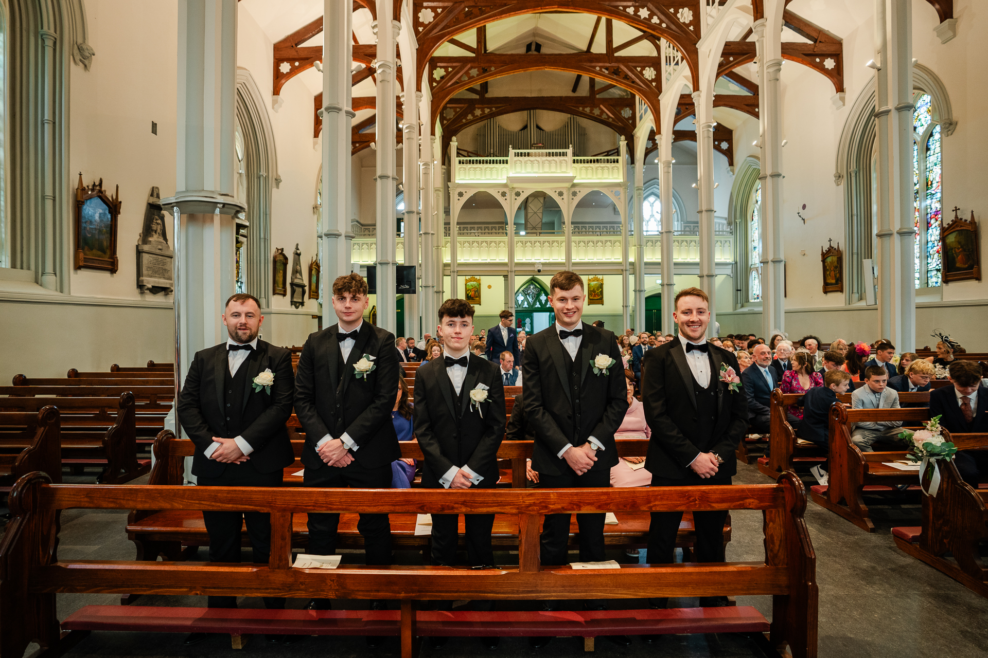 A group of men in suits standing on a wooden pews