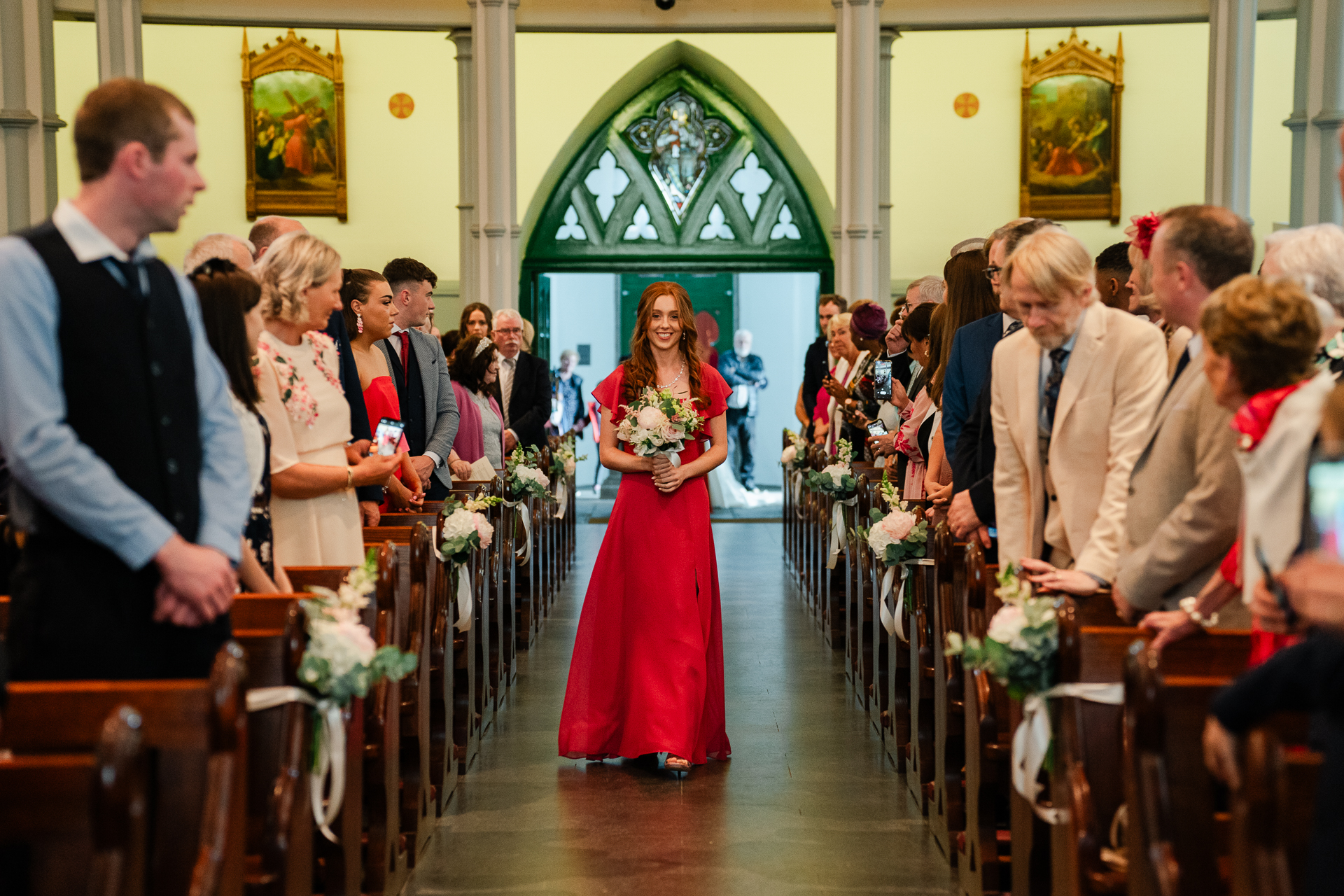 A person in a red dress standing in a church with a group of people