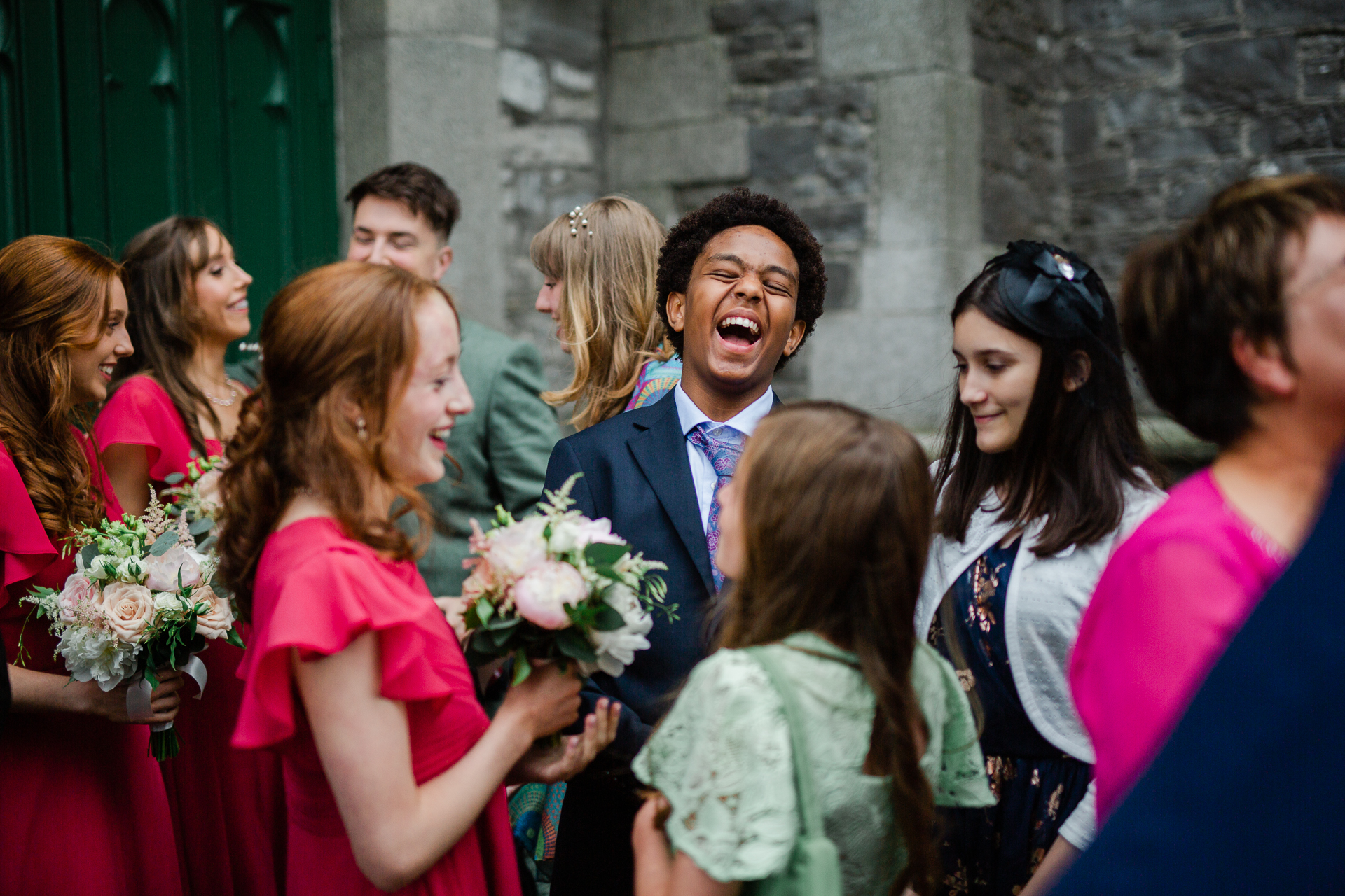 A person in a suit laughing with a group of people around him