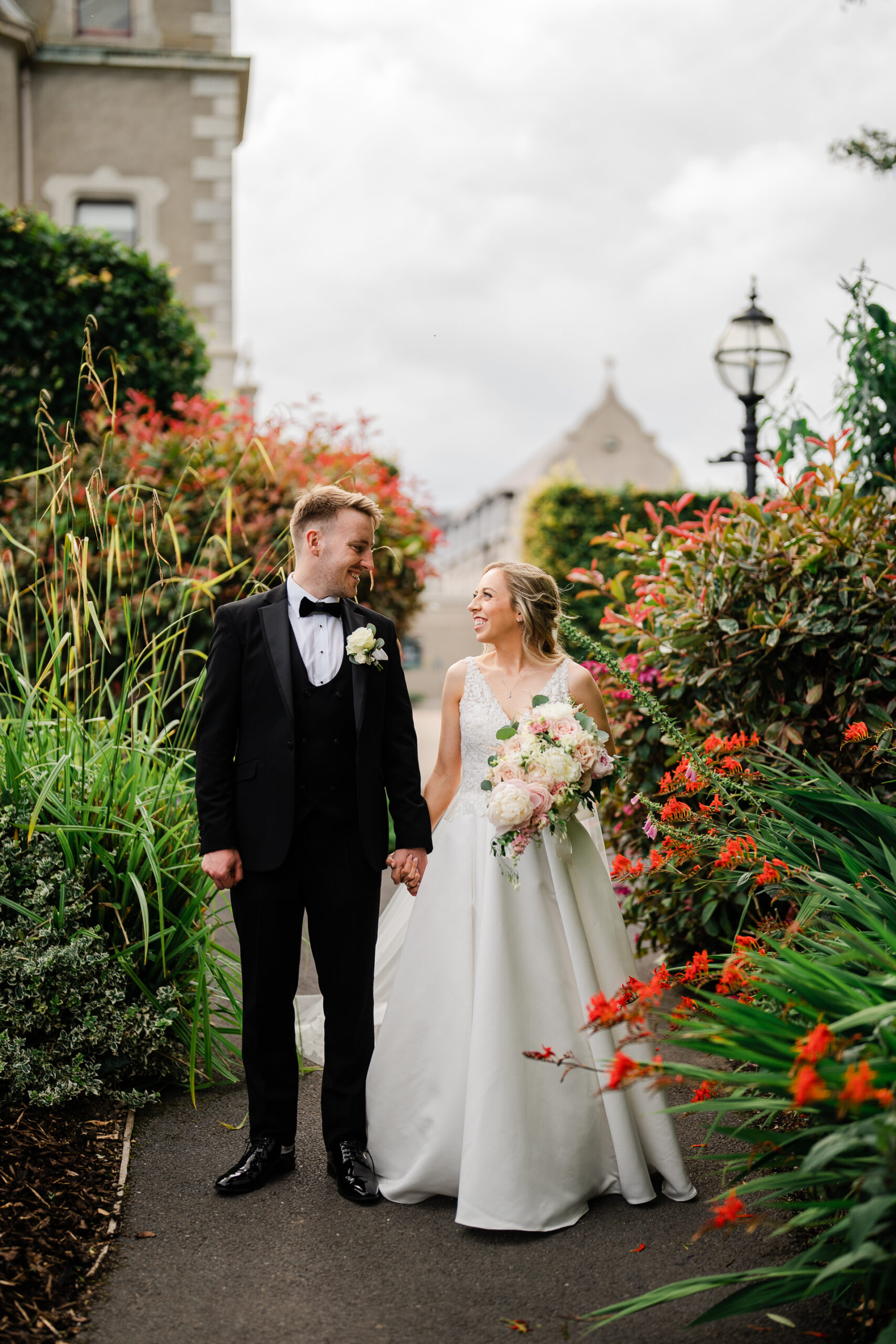 A man and woman walking down a path with flowers and plants