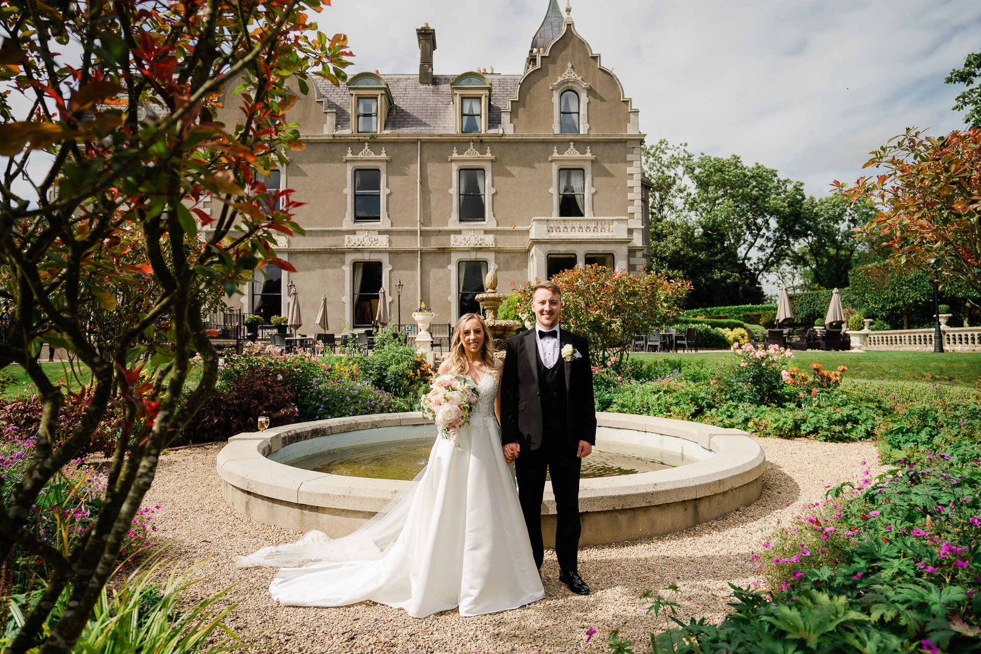 A man and woman posing for a picture in front of a mansion