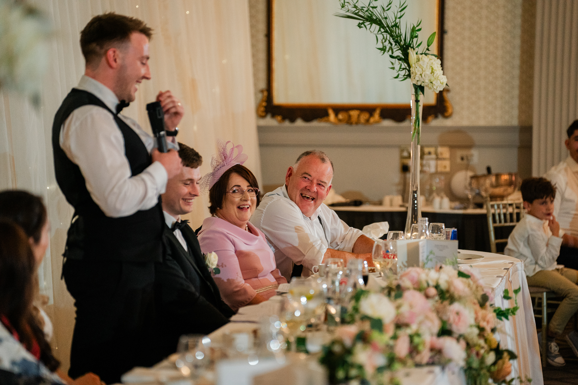 A man speaking into a microphone to a woman sitting at a table