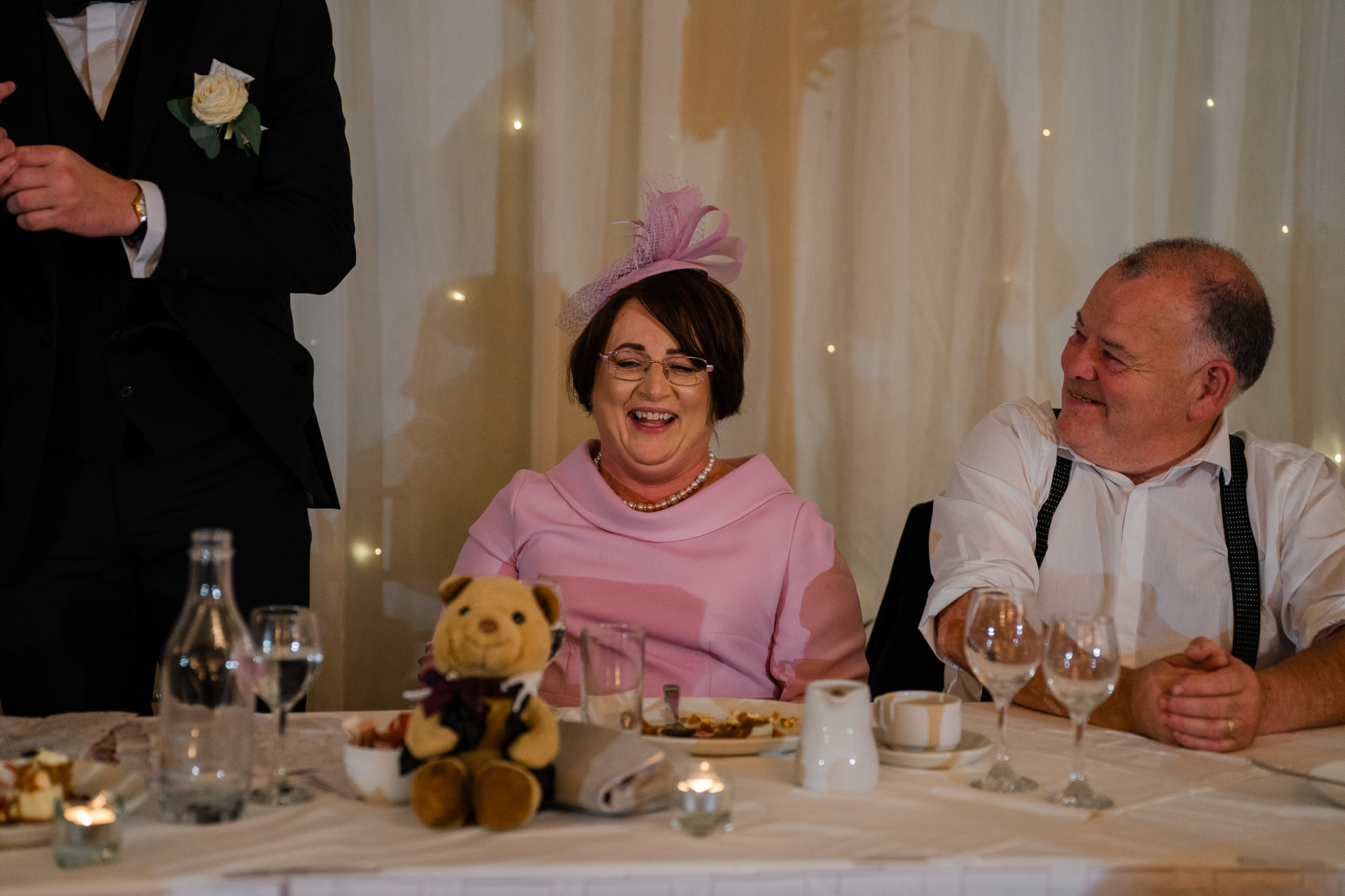 A man and a woman sitting at a table with a teddy bear